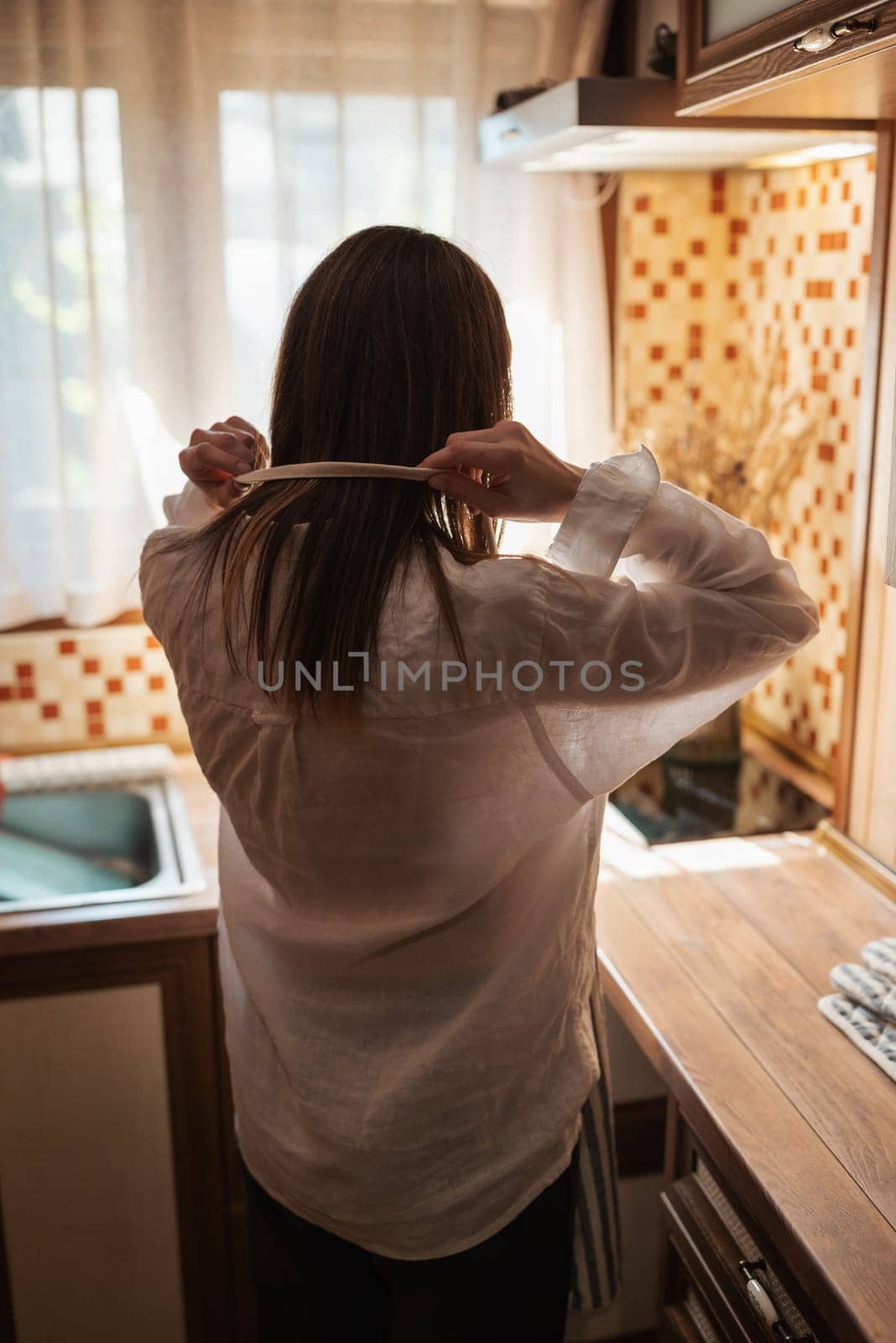 Girl standing in kitchen put on an apron by VitaliiPetrushenko