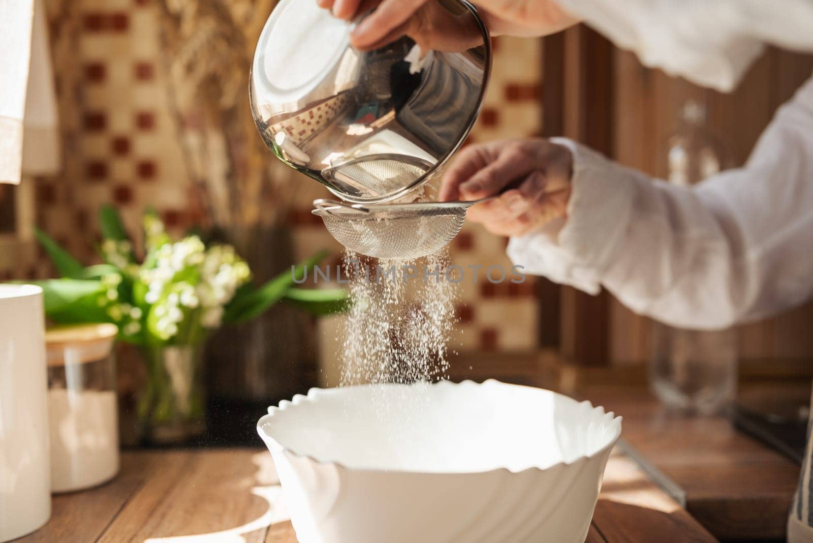 Woman sieving flour for dough by VitaliiPetrushenko