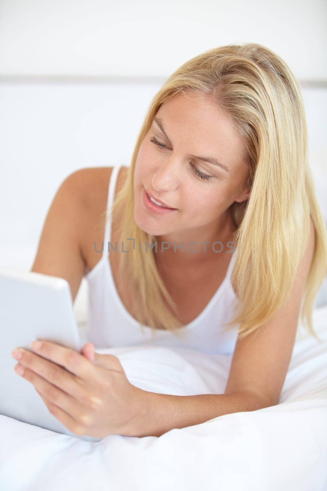 Home, internet and woman with a tablet, typing and communication with network, social media and relax. Person, apartment and girl with technology, connection and digital app with a smile and bedroom by YuriArcurs