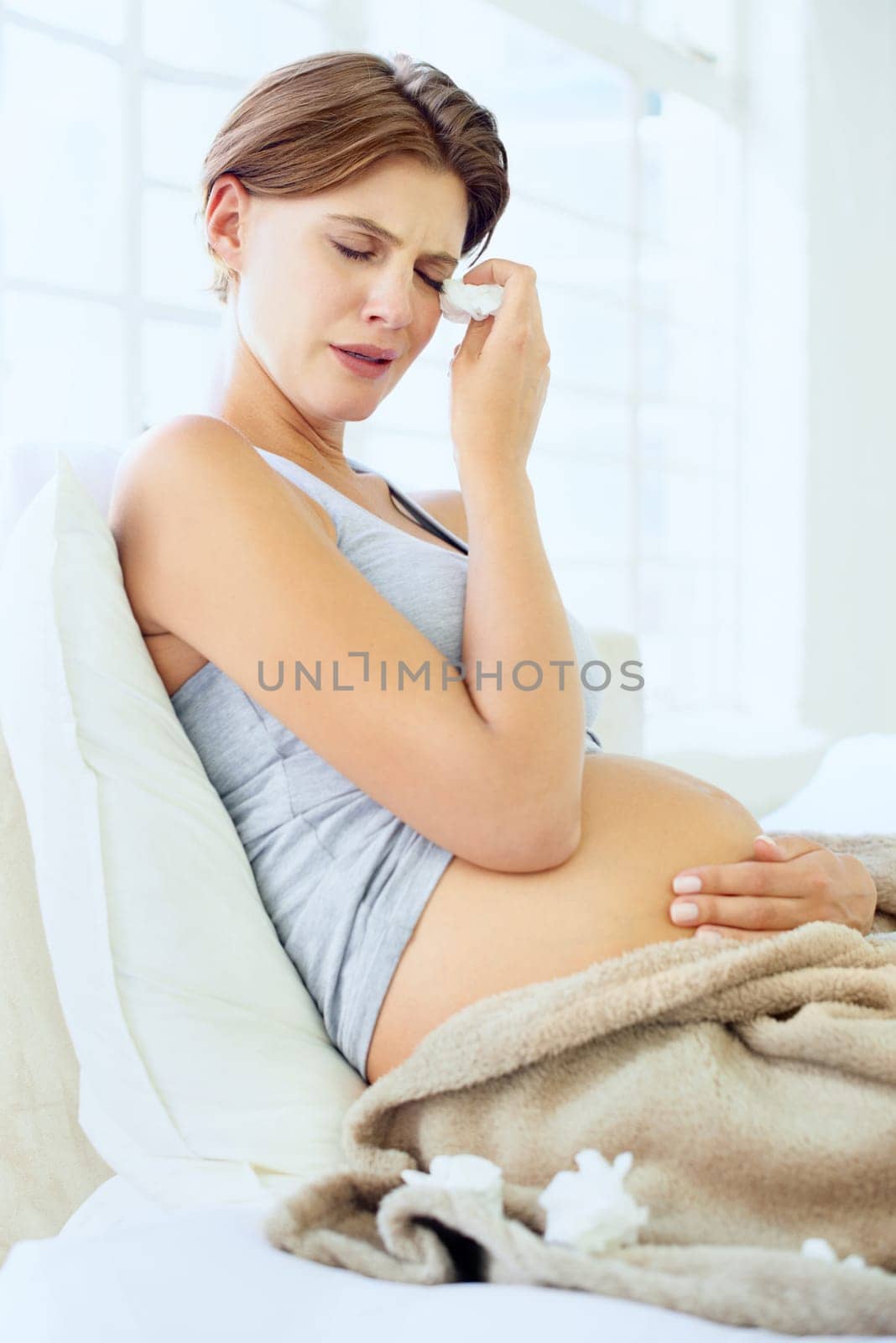 Crying, tissue and pregnant woman in a bed with depression, worry or fear for the future at home. Maternity, anxiety or person in bedroom with pregnancy mood swings, hormones or overwhelmed in house by YuriArcurs