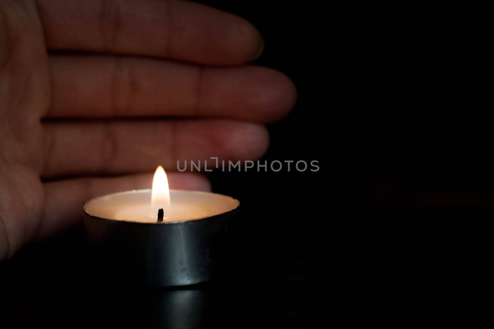 Candle and hand close up in the dark, copy space