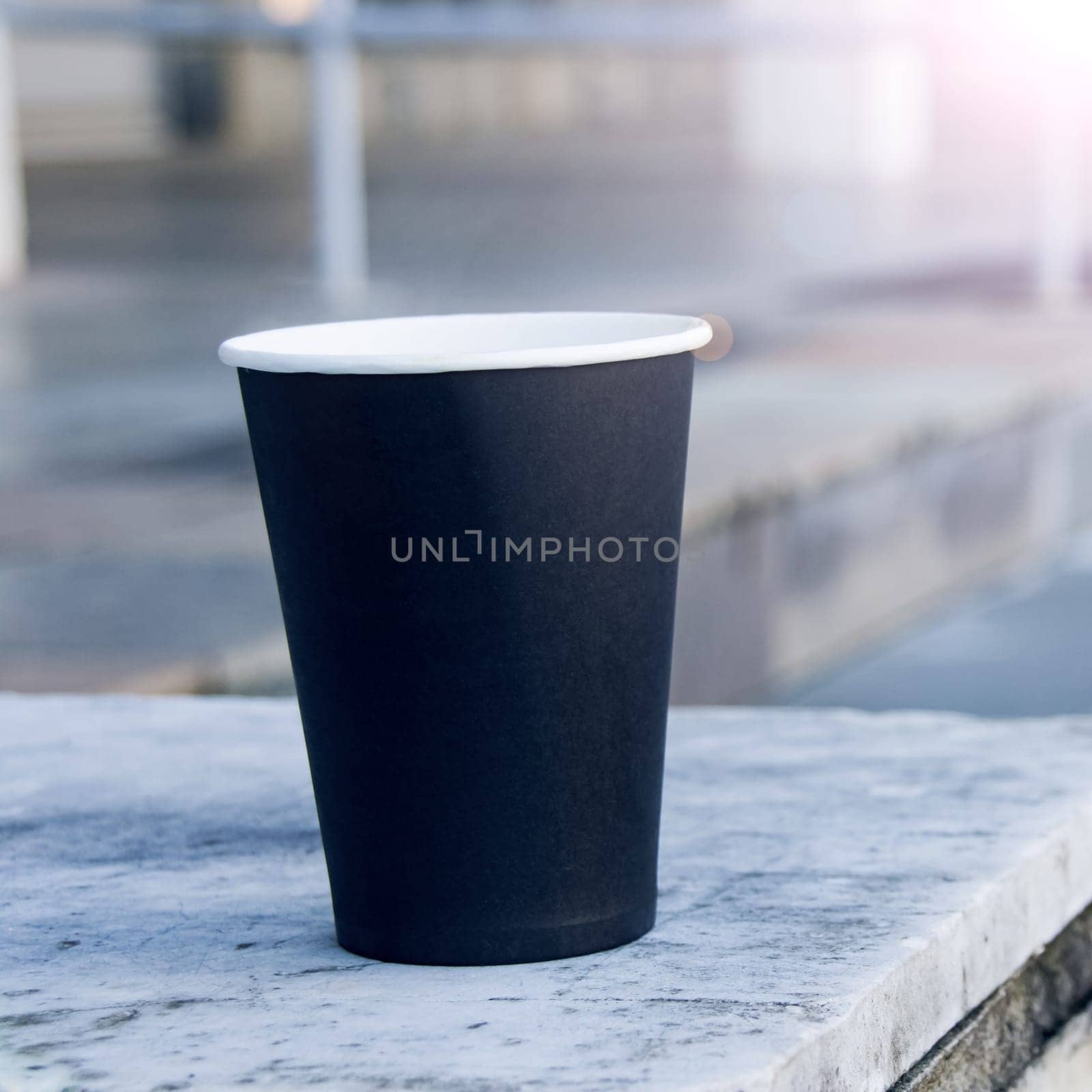 Black paper cup of coffee on stairs background, square format