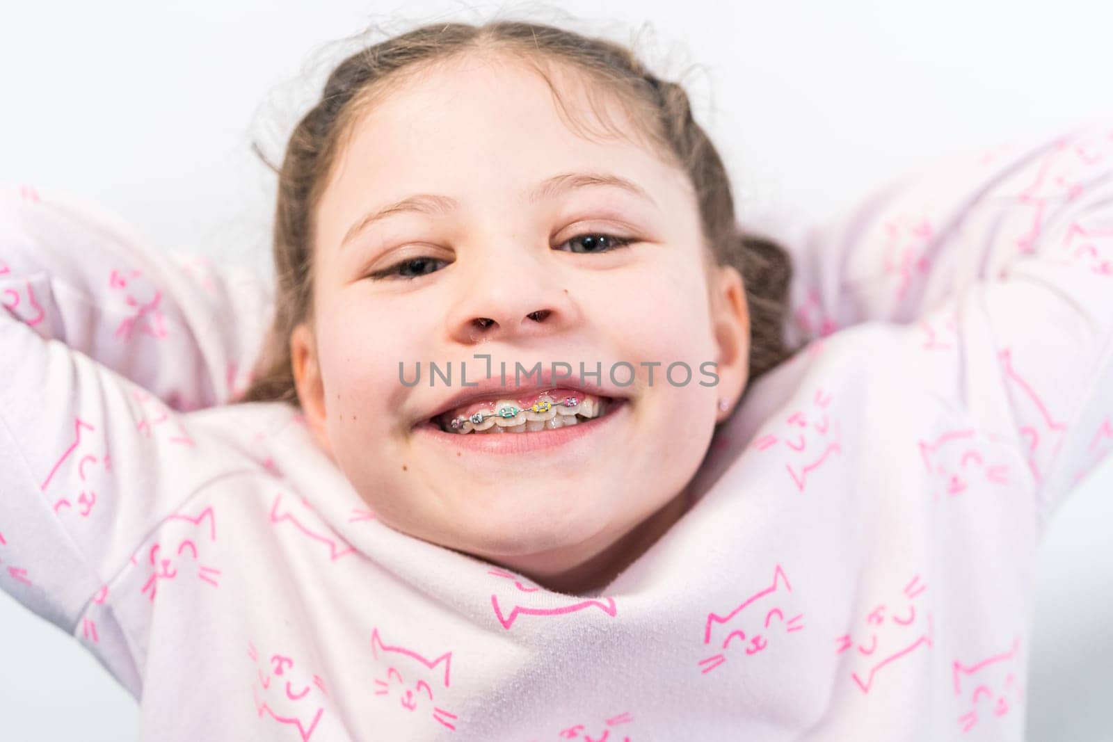 Little girl with rainbow braces smiling at the camera.