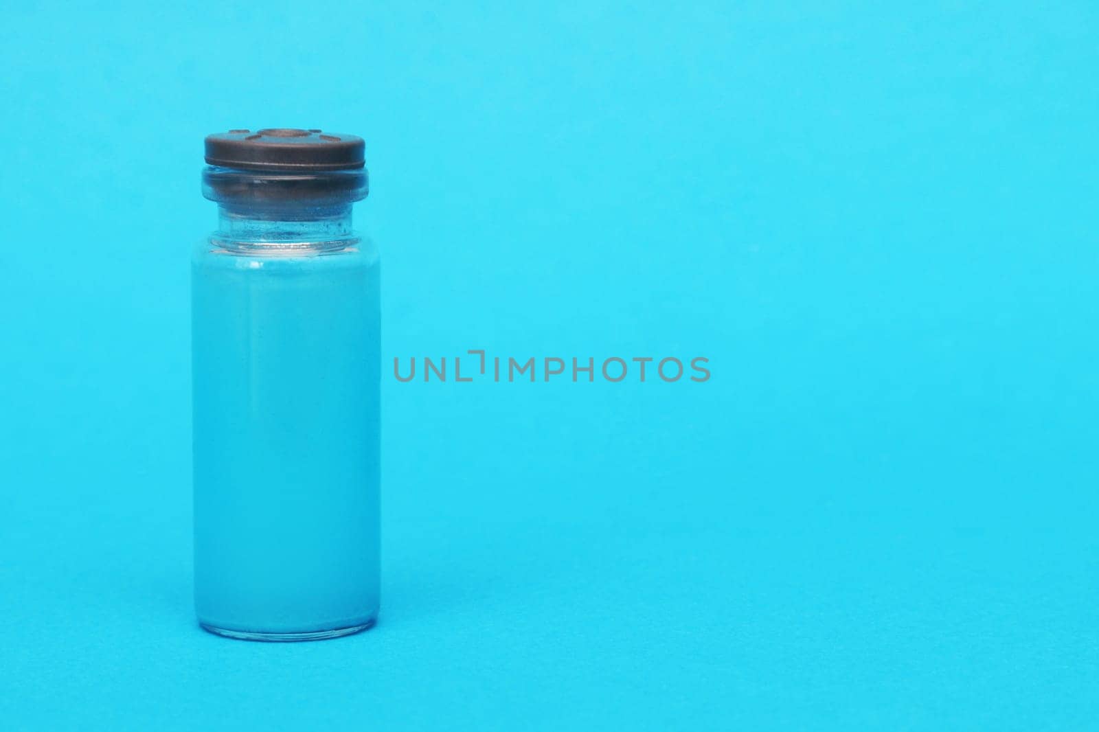 Glass ampoule with blue liquid on a blue background. by gelog67
