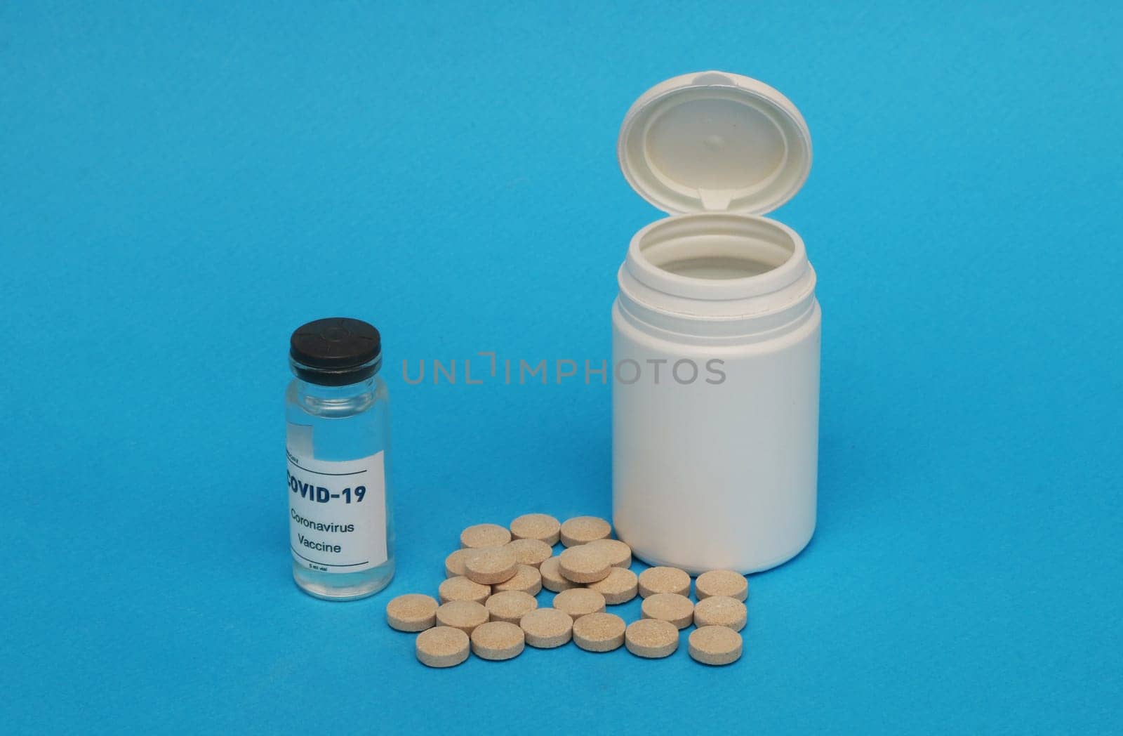 Plastic white bottle, brown pills, covid-19 vaccine ampoule on a blue background.