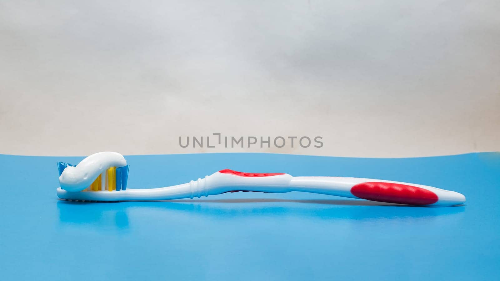 Toothbrush and toothpaste on a blue background close up