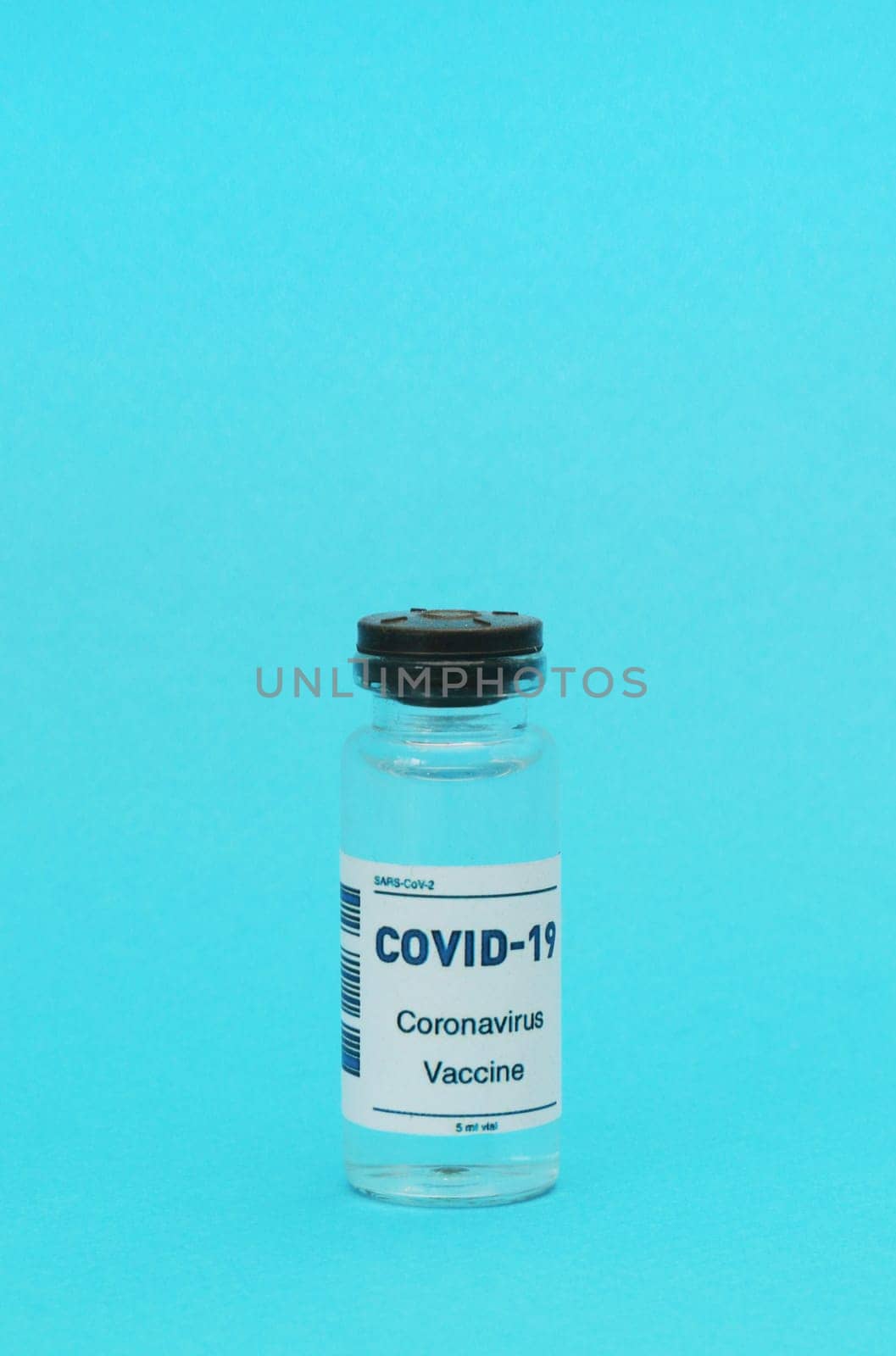 Vertical photo of an empty glass bottle from the Covid-19 vaccine on a blue background. Medical concept.