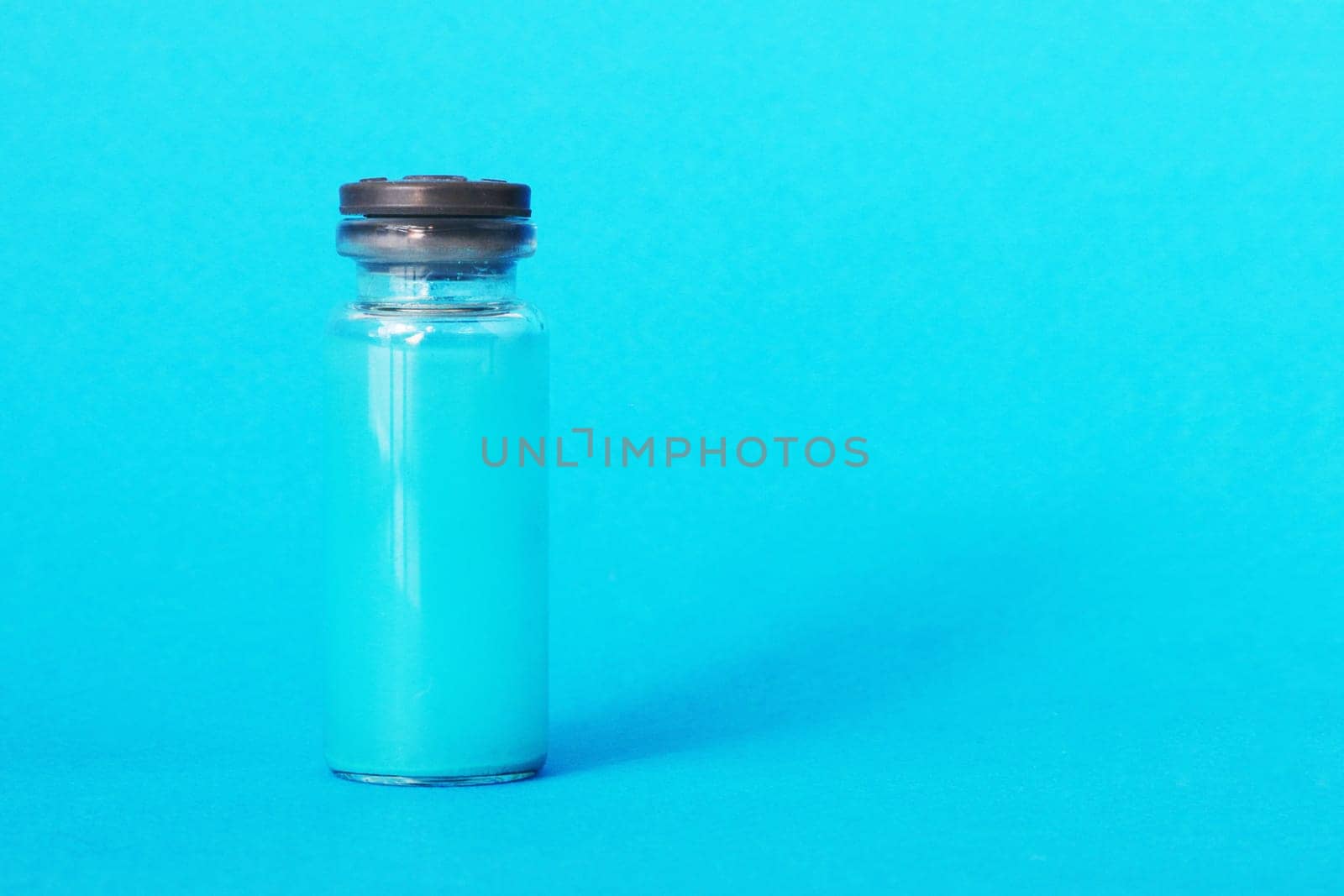 A bottle with a blue chemical reagent for research on a blue background.