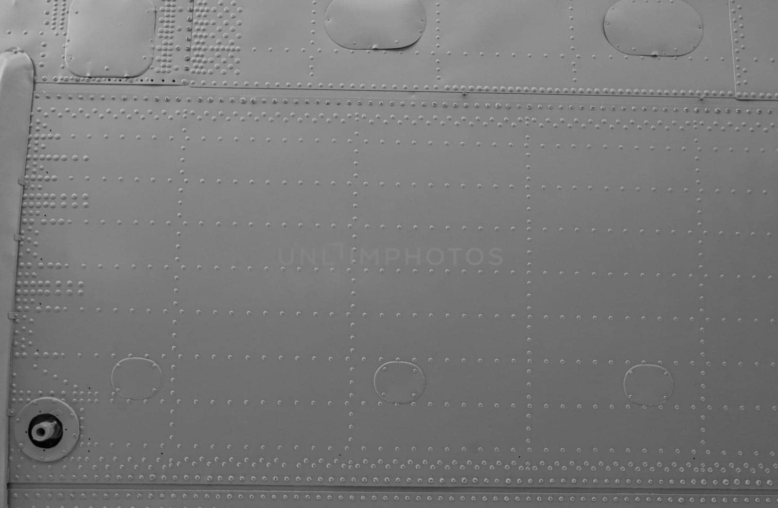 Aircraft skin close up. Rivets on gray metal. Iron panel of airplane. Abstract metal background.