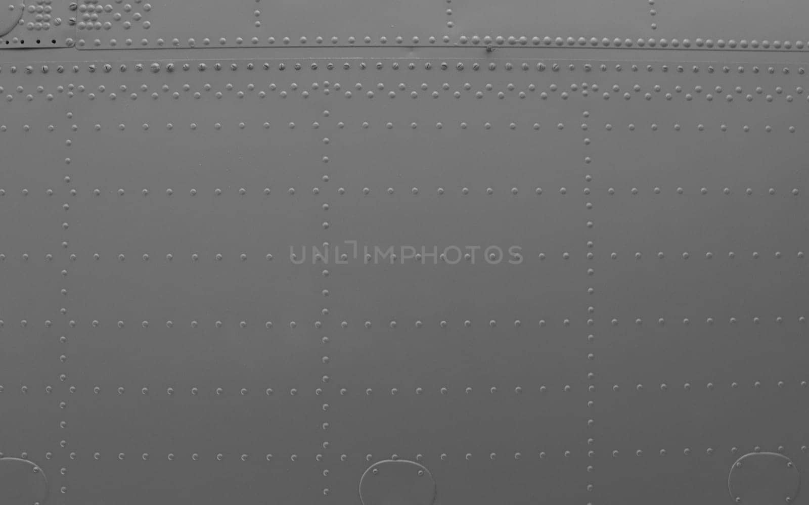 Aircraft skin close up. Rivets on gray metal. Aluminum surface of the aircraft fuselage. ..Abstract metal background.