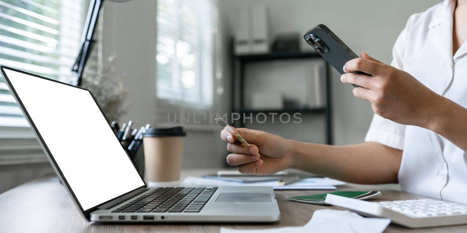 Young woman makes a purchase on the Internet on the laptop with credit card and mockup laptop blank screen.