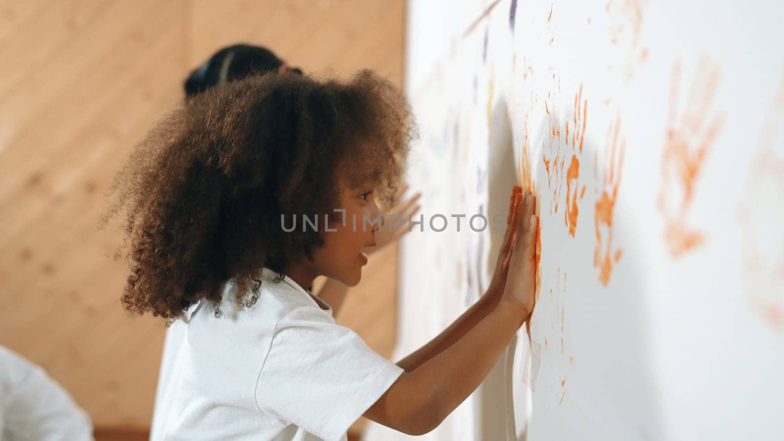 African girl paint the wall with colorful stained hands with friend. Erudition. by biancoblue