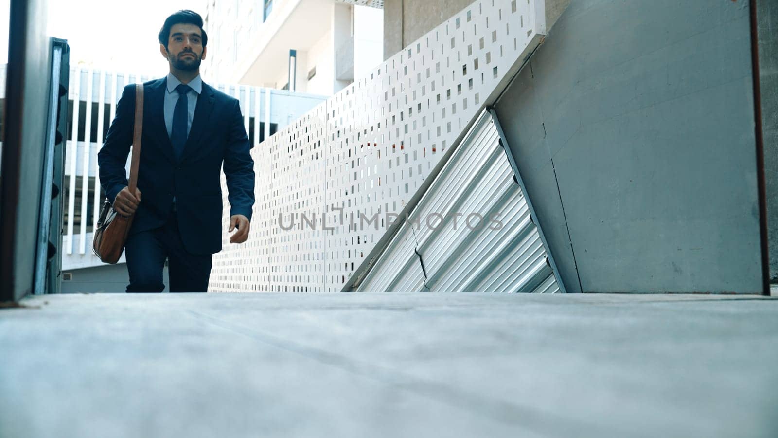 Smart business man walking up the stairs with confident near building. Skilled project manger walking on stairs seeking for job, going for new job near at modern skyscraper. Copy space. Exultant.