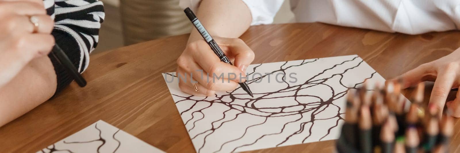 TVER, RUSSIA - FEBRUARY 25, 2023: Womans draws neurographics at table at a psychological session, neurographic pencil drawing to remove restrictions, art therapy.