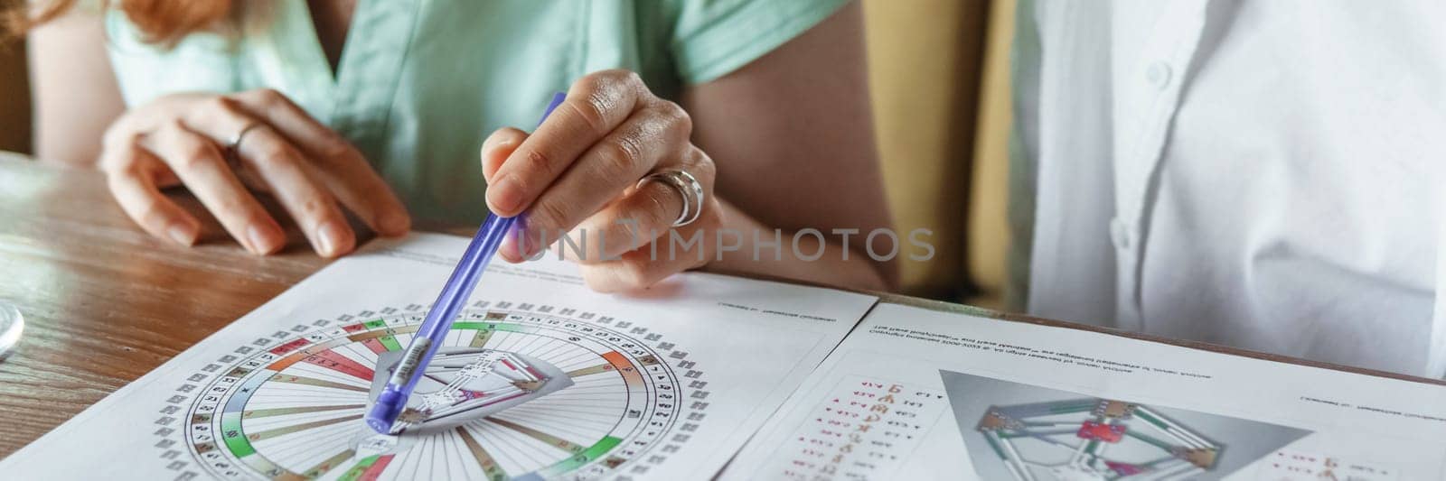 Tver, Russia - August 2, 2021. A woman in a cafe at a table is studying the design of a person. The concept of studying esoteric sciences. A bodigraph or a map of a person on an A4 sheet