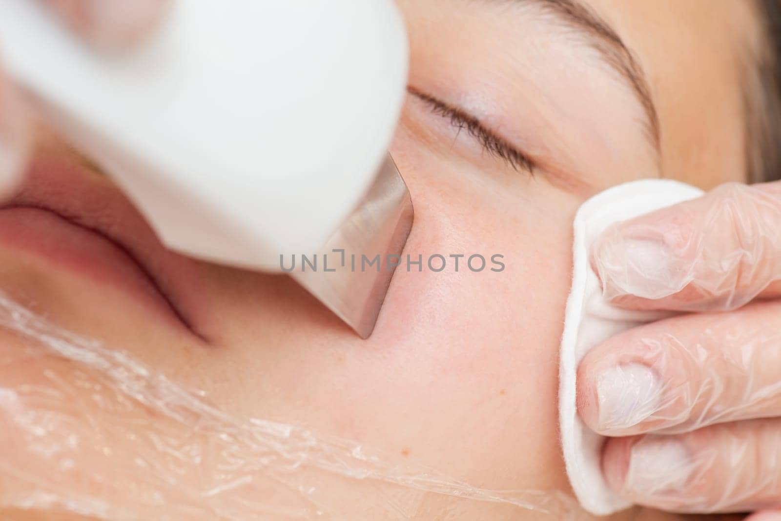 Macro shot of procedure of ultrasound face cleaning to a young girl