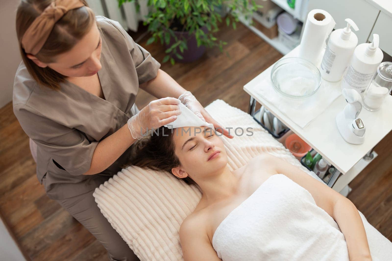 Professional cosmetologist executing cleaning of a face in modern health and beauty clinic