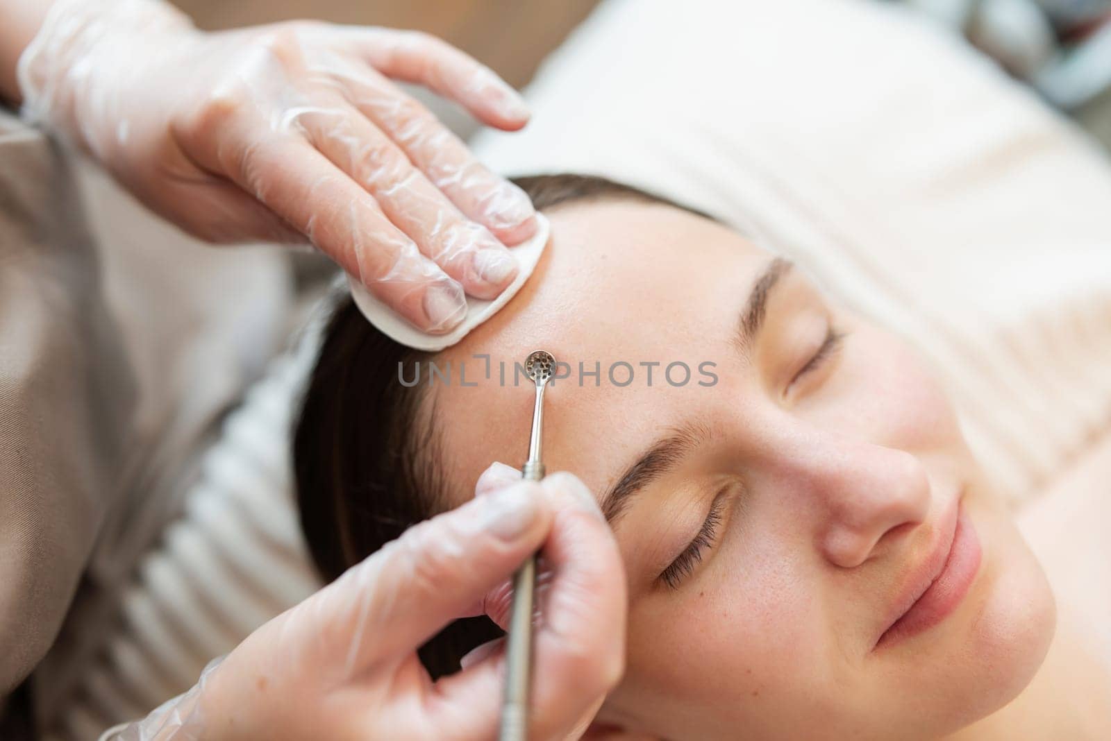 Close up of hands of a doctor cleaning skin on face of a client in cosmetology clinic