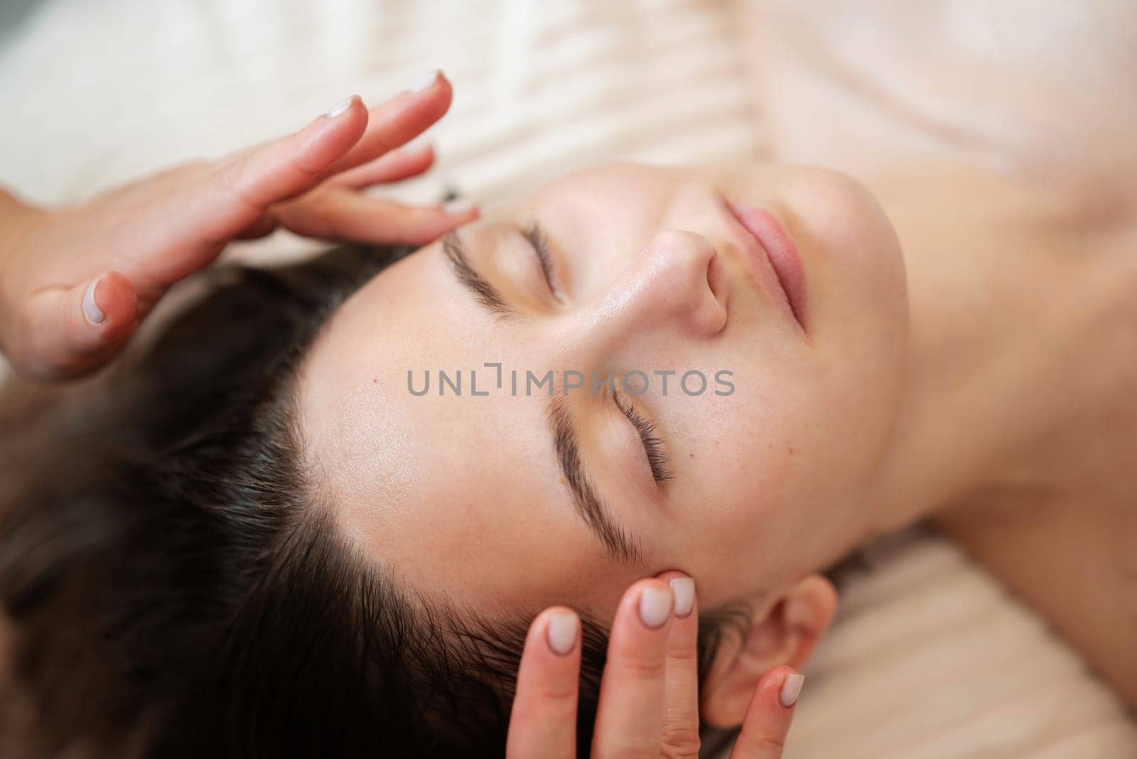 Close up of face of a girl client getting relaxation treating facial massage by VitaliiPetrushenko