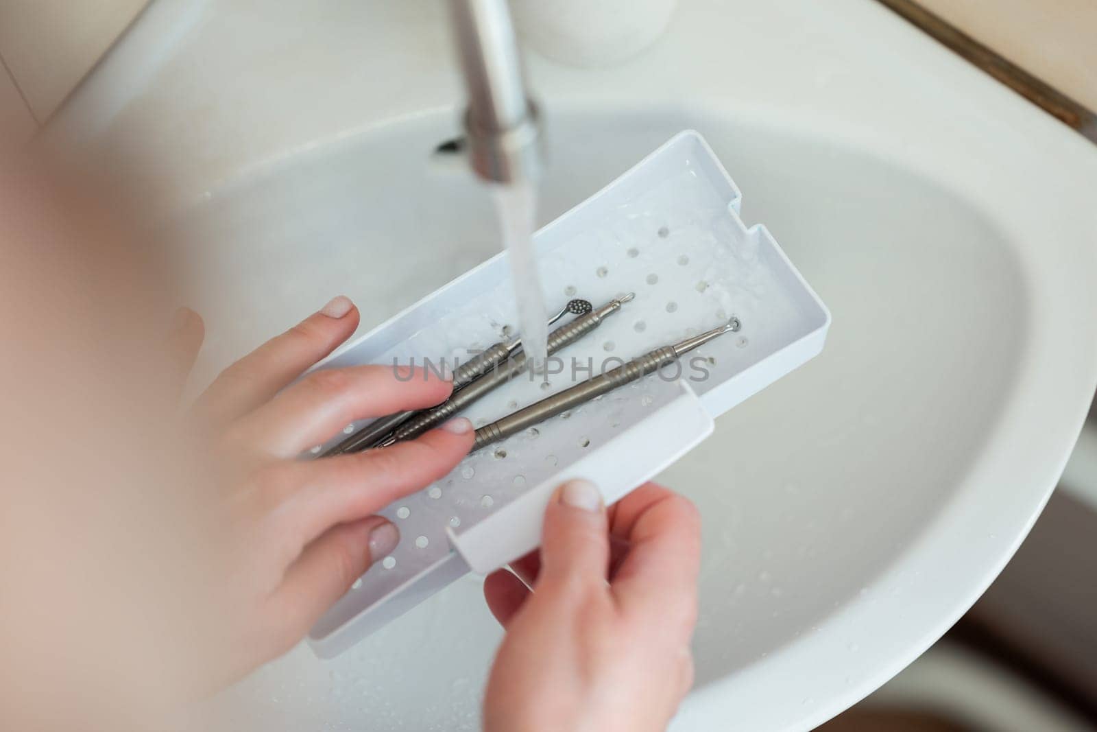 Washing cosmetological tools for skin cleaning under the tap after using them