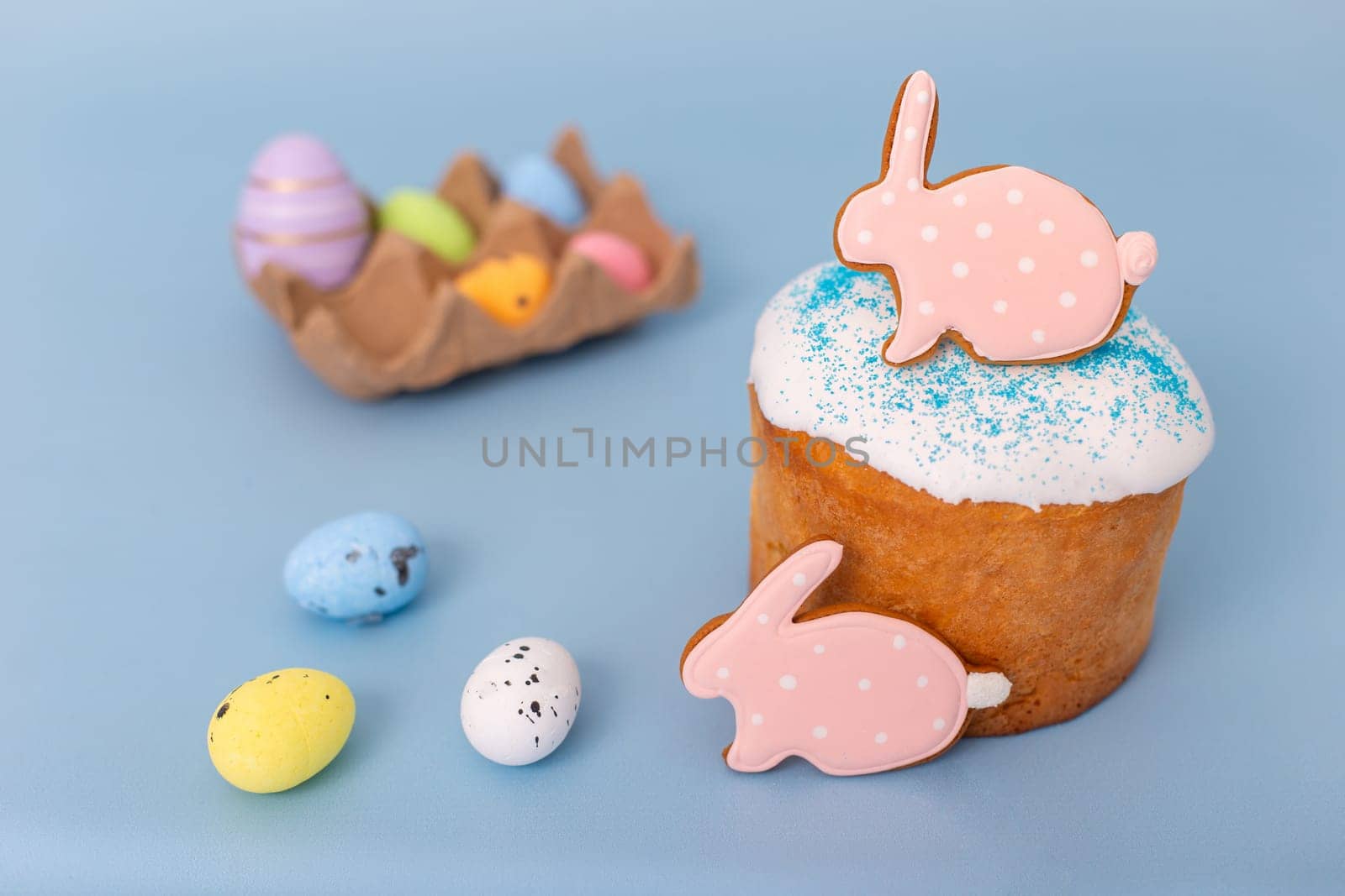 Beautiful easter still life with gingerbread in the form of a rabbit on an Easter cake, small decorative multicolored eggs lie next to it.