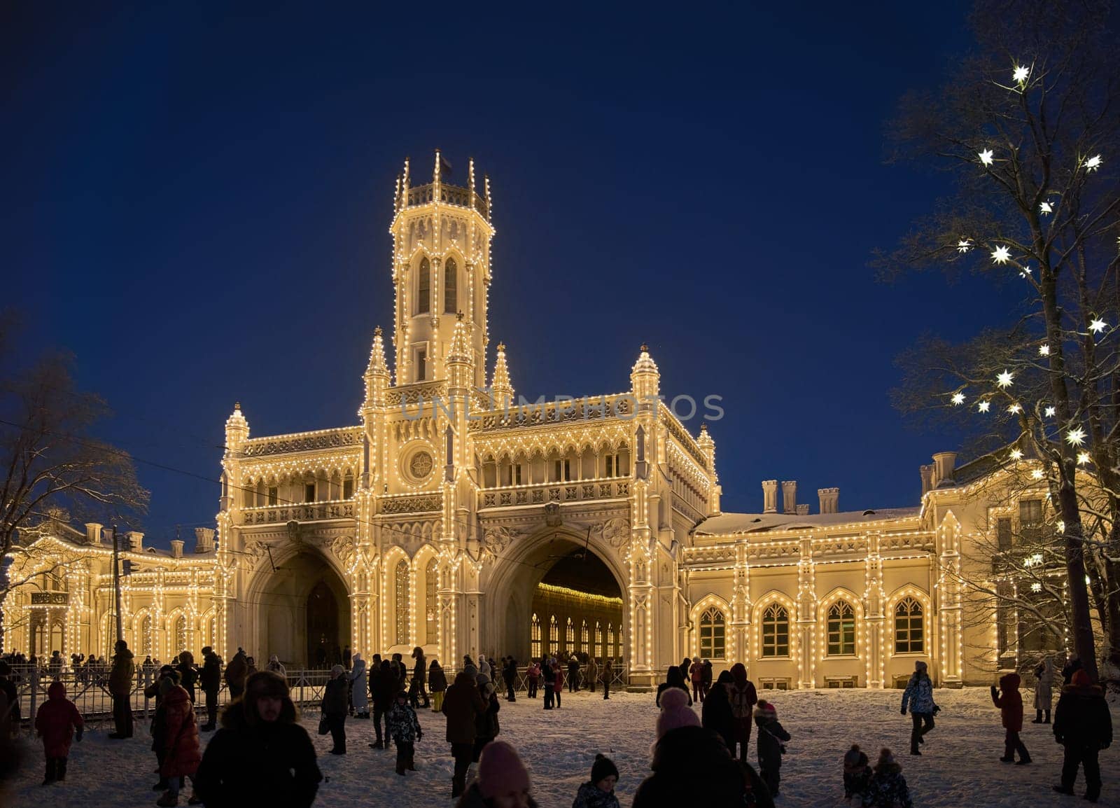 Russia, Peterhof, St.Petersburg, 07 January 2024: Magical illumination of the building of the New Peterhof railway station near St. Petersburg on a winter evening, Christmas decorations on trees. High quality photo