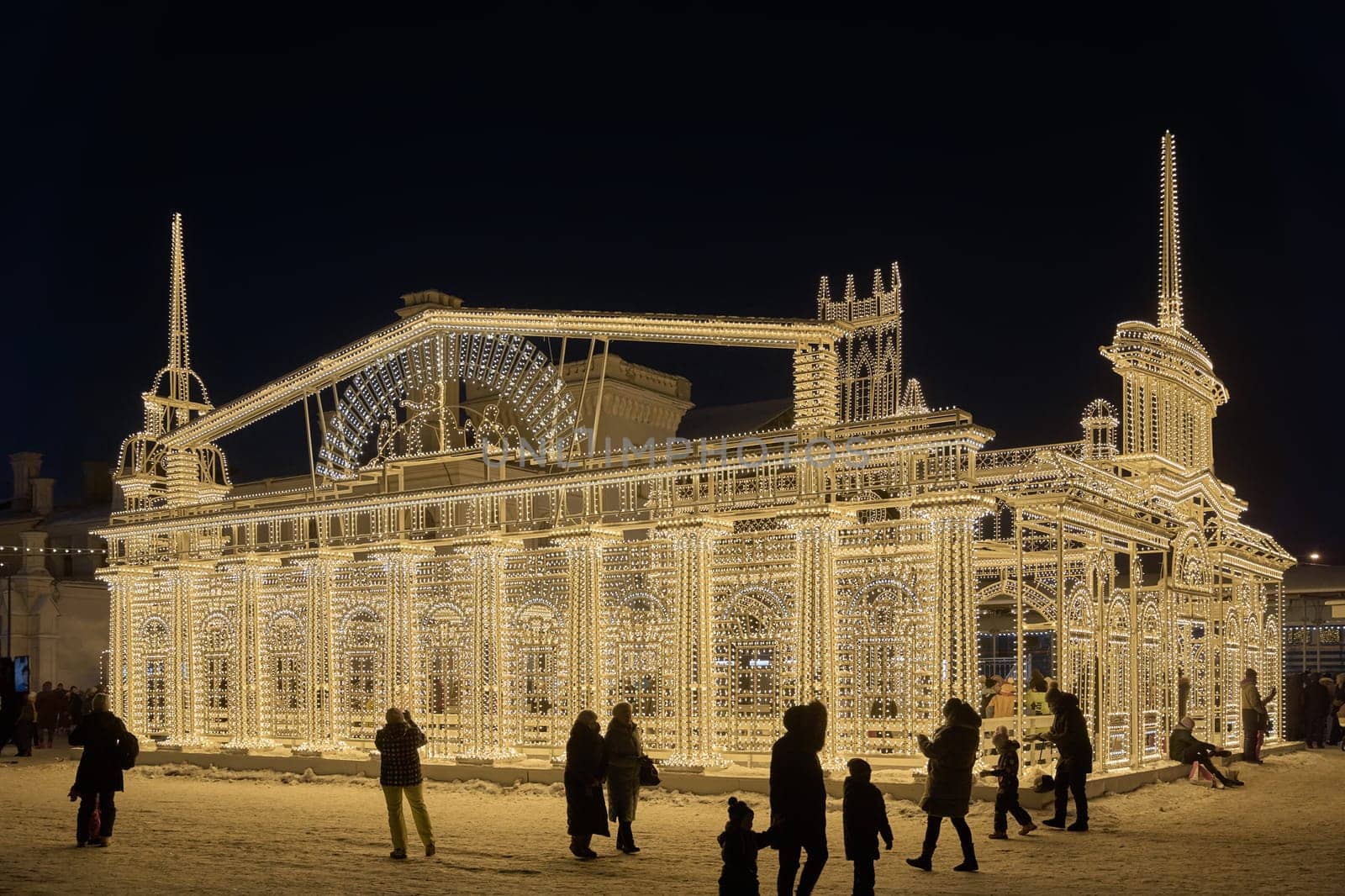 Russia, Peterhof, St.Petersburg, 07 January 2024: Magical illumination of the building of an ice rink decorated with light reliefs of the city's attractions, railway station, Christmas decorations. High quality photo