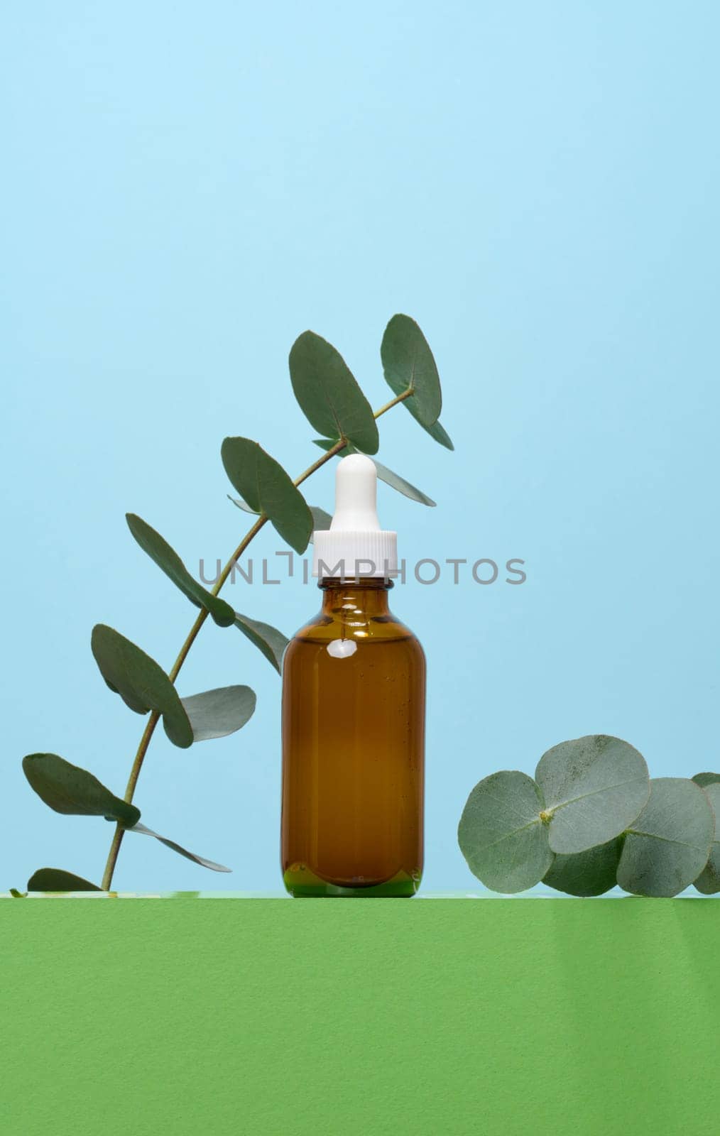 A glass brown bottle with a dropper on a blue background, a container for cosmetic products. 