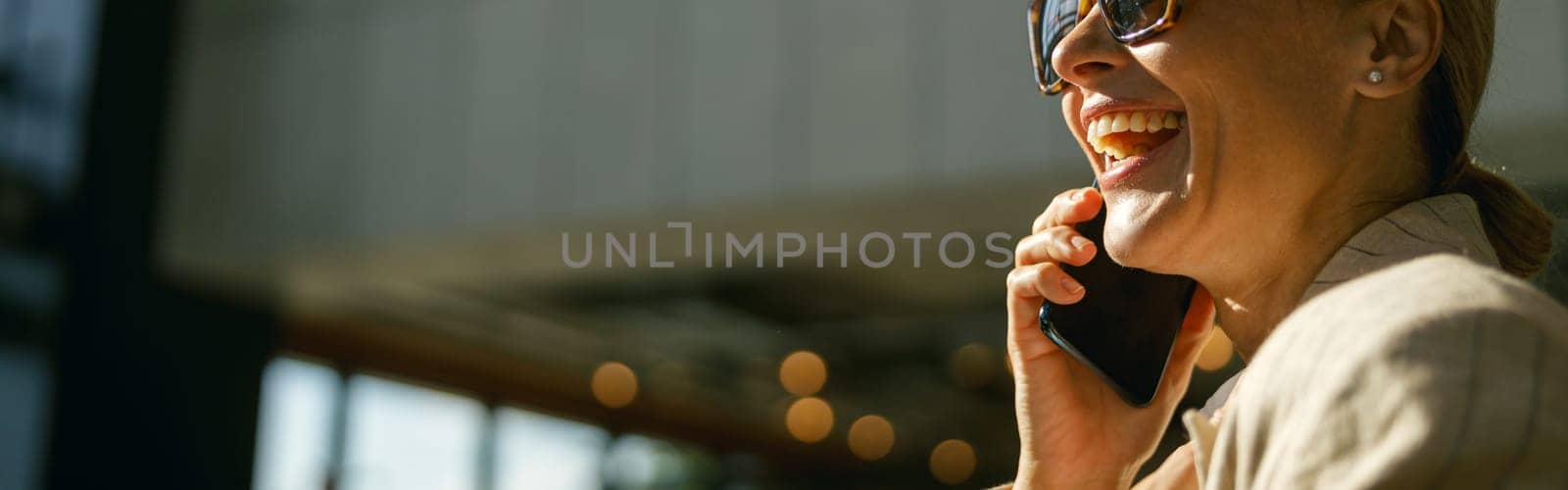 Close up of business woman in eyeglasses talking phone with client on modern office background