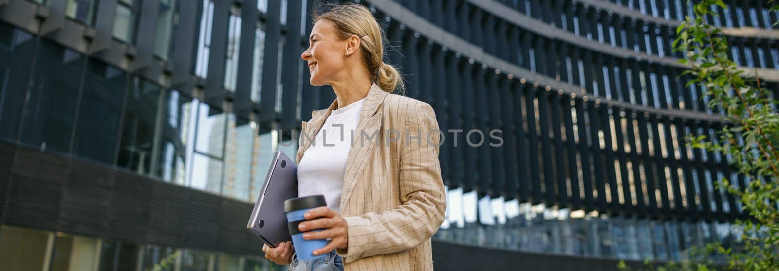 Stylish business woman drinking coffee during break time near modern office building and looks away by Yaroslav_astakhov