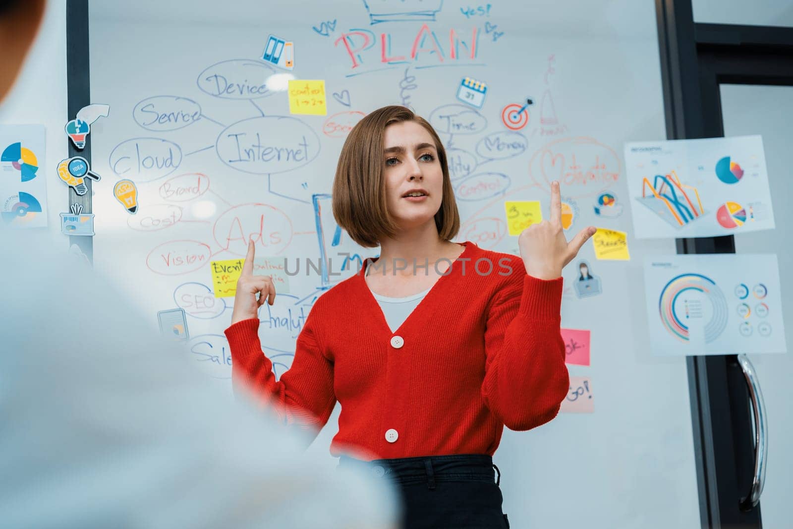 Professional attractive female leader presents creative marketing plan by using brainstorming mind mapping statistic graph and colorful sticky note at modern business meeting room. Immaculate.