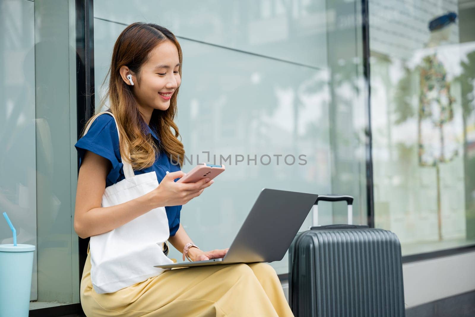 A beautiful woman works remotely on her laptop computer while waiting for her train. She's able to balance work and travel with ease, thanks to modern technology. new age of productivity.