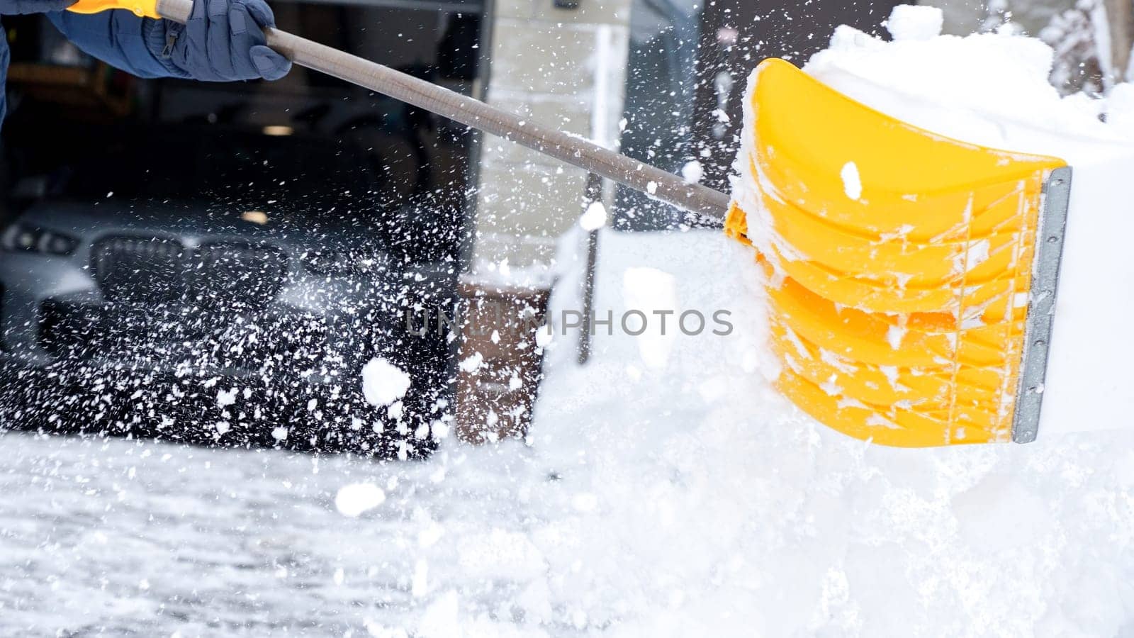 Man shoveling snow off of his driveway after a winter storm in Canada. Man with snow shovel cleans sidewalks in winter. Winter time. by JuliaDorian