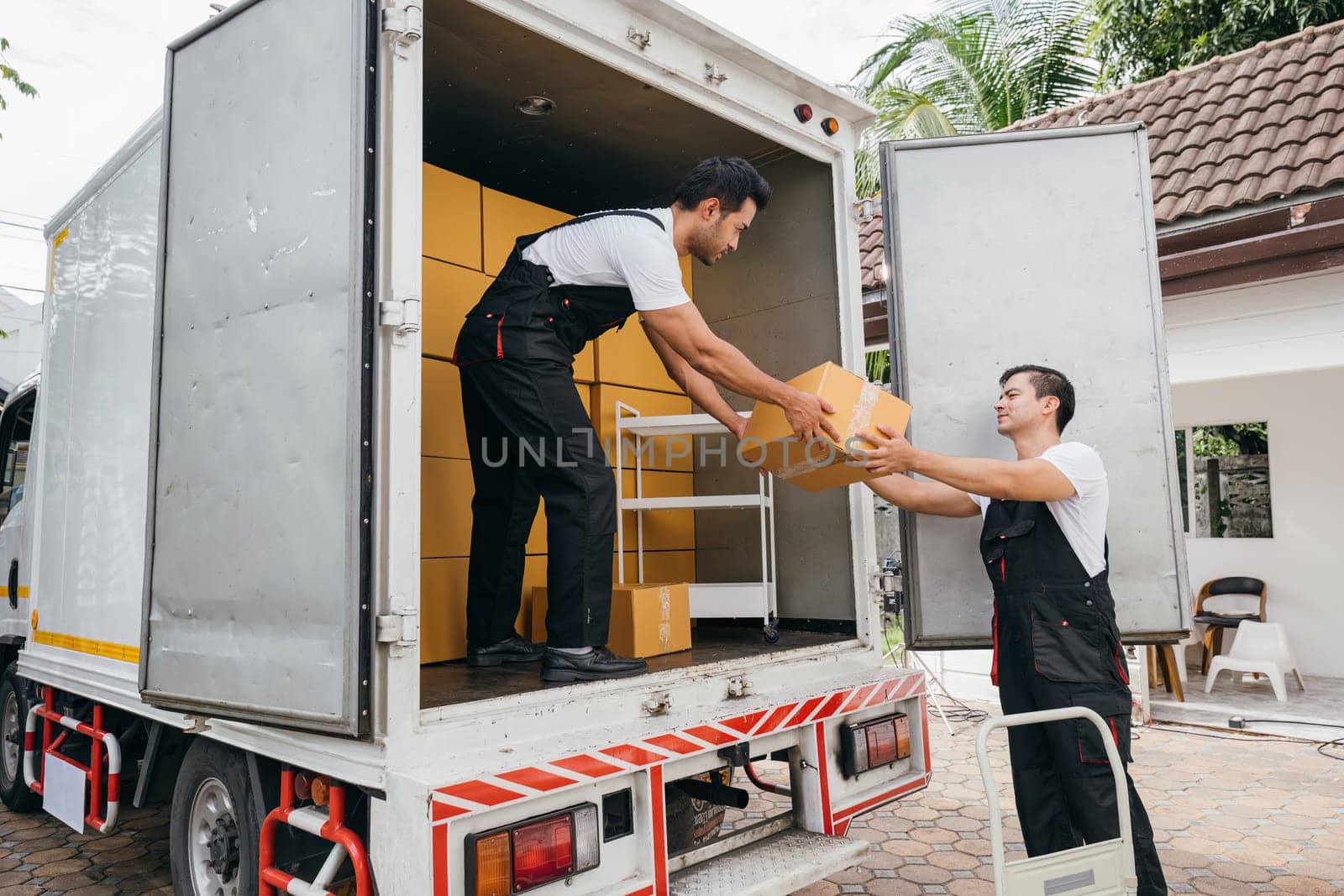 Employee team unloads boxes from truck for customer moving house showcasing the company dedication to efficient service and customer happiness. Moving Day