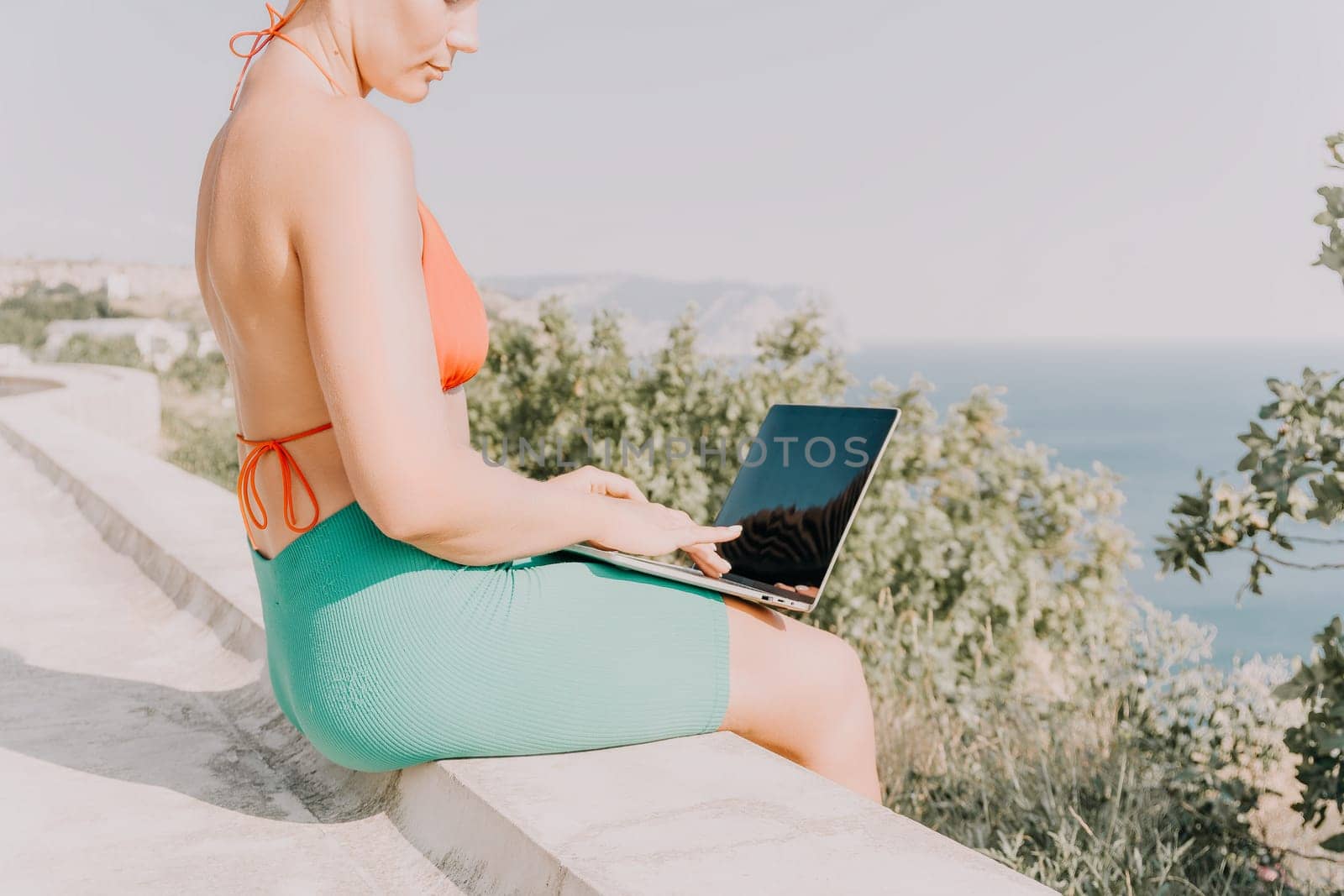 Woman laptop park. Working remotely on seashore. Happy successful woman female freelancer working on laptop at summer sunset, makes a business transaction online. Freelance, remote work on vacation by panophotograph