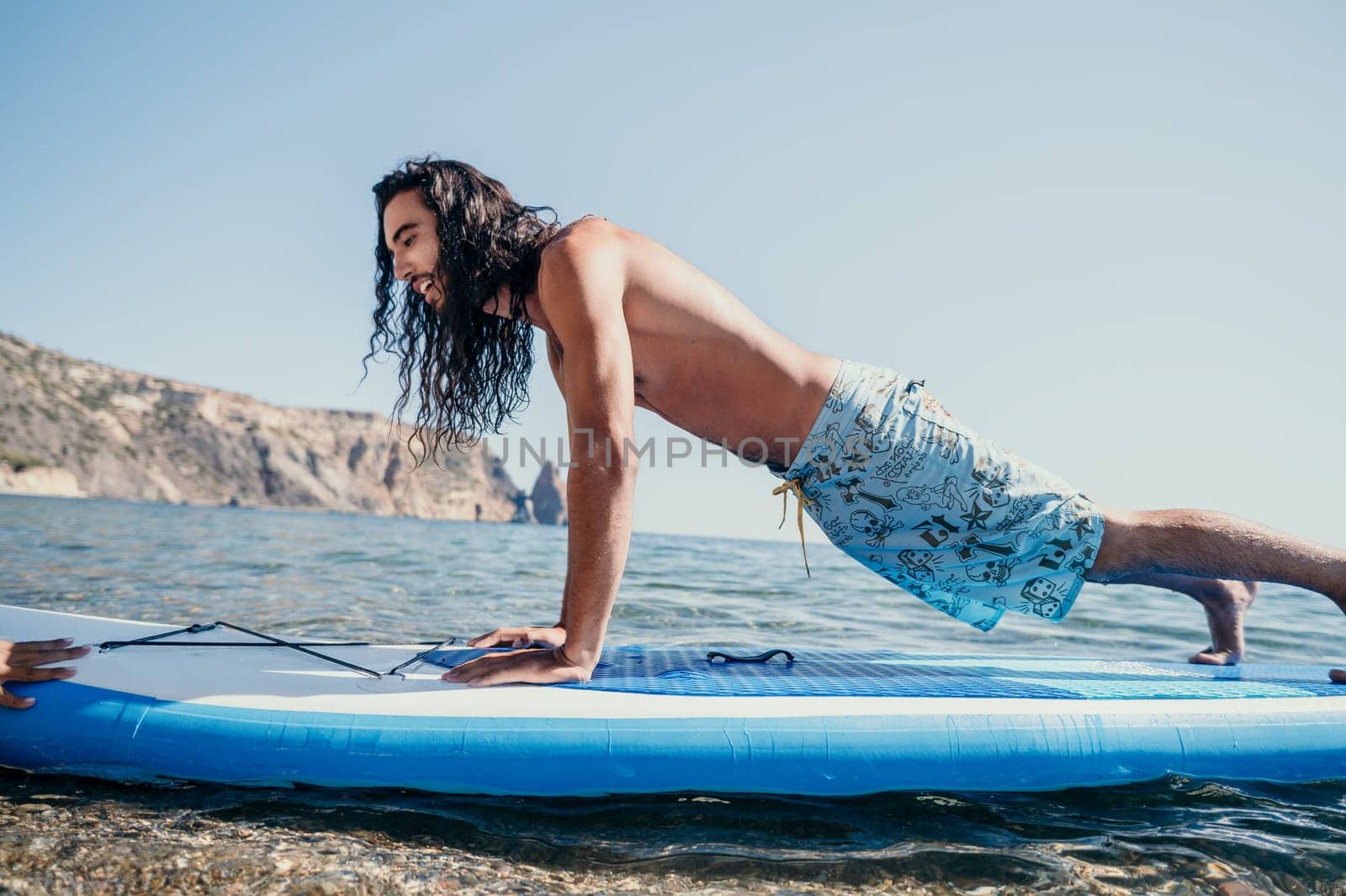 man sup yoga. Happy sporty man practising yoga pilates on paddle sup surfboard. male stretching doing workout on sea water. Modern individual male hipster outdoor summer sport activity. by panophotograph