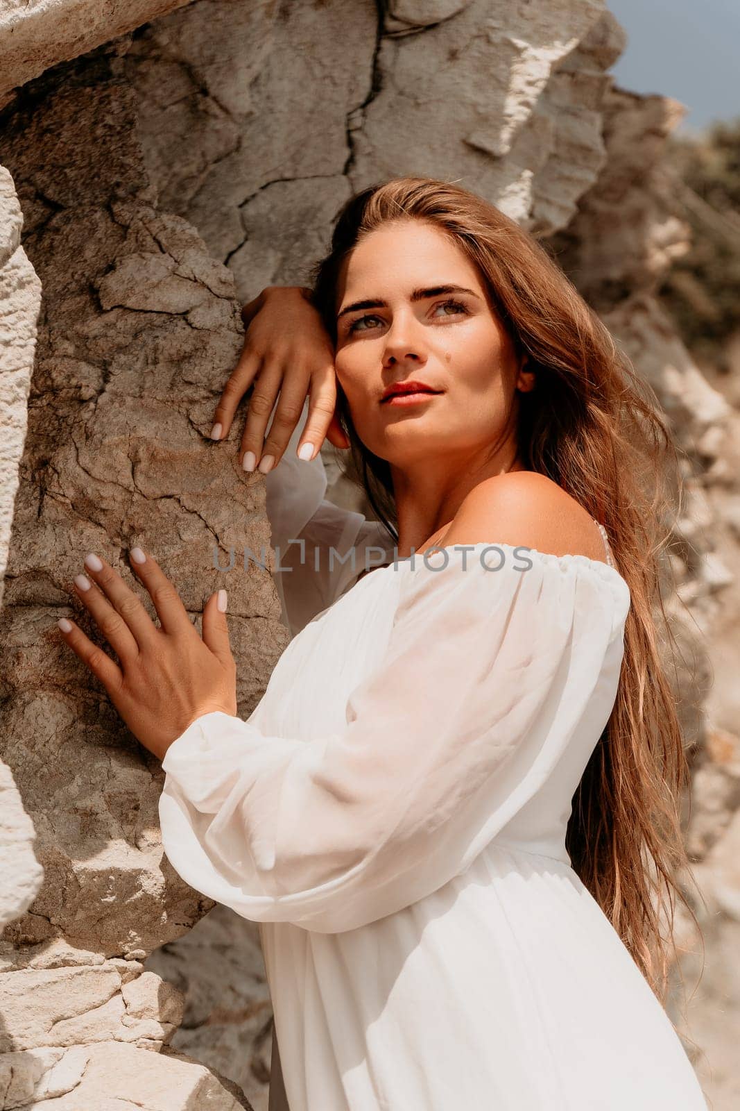 Woman summer travel sea. Happy lady with long hair in white dress enjoy taking photo outdoors for memories. Woman traveler posing on beach at sea surrounded by volcanic mountains, sharing emotions by panophotograph