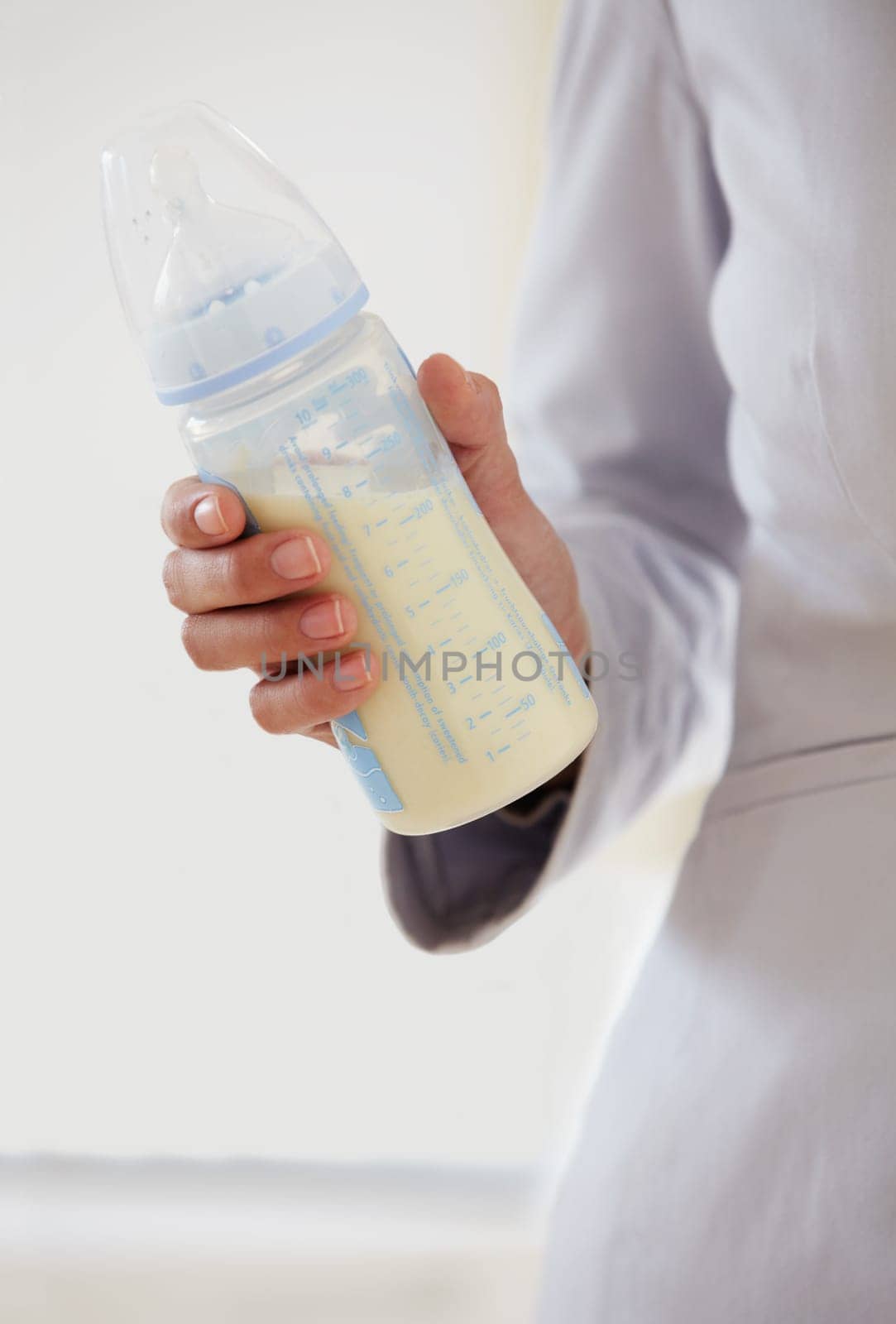 Business, woman and baby bottle with mom in suit, working and balance a career with motherhood. Hand, closeup and mother with milk in container for child, care and management of family with a job by YuriArcurs