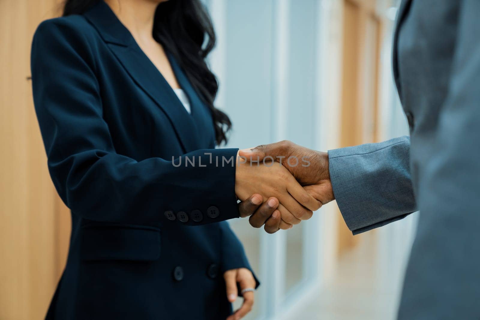 Closeup of business hands shaking between businesswoman and professional male leader at modern office corridor. Represented unity, corporate, collaborate, teamwork cooperation, joining. Ornamented.