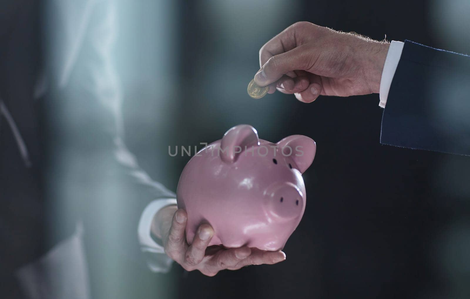 Hand puts a coin in a piggy bank on a black background. accumulation concept