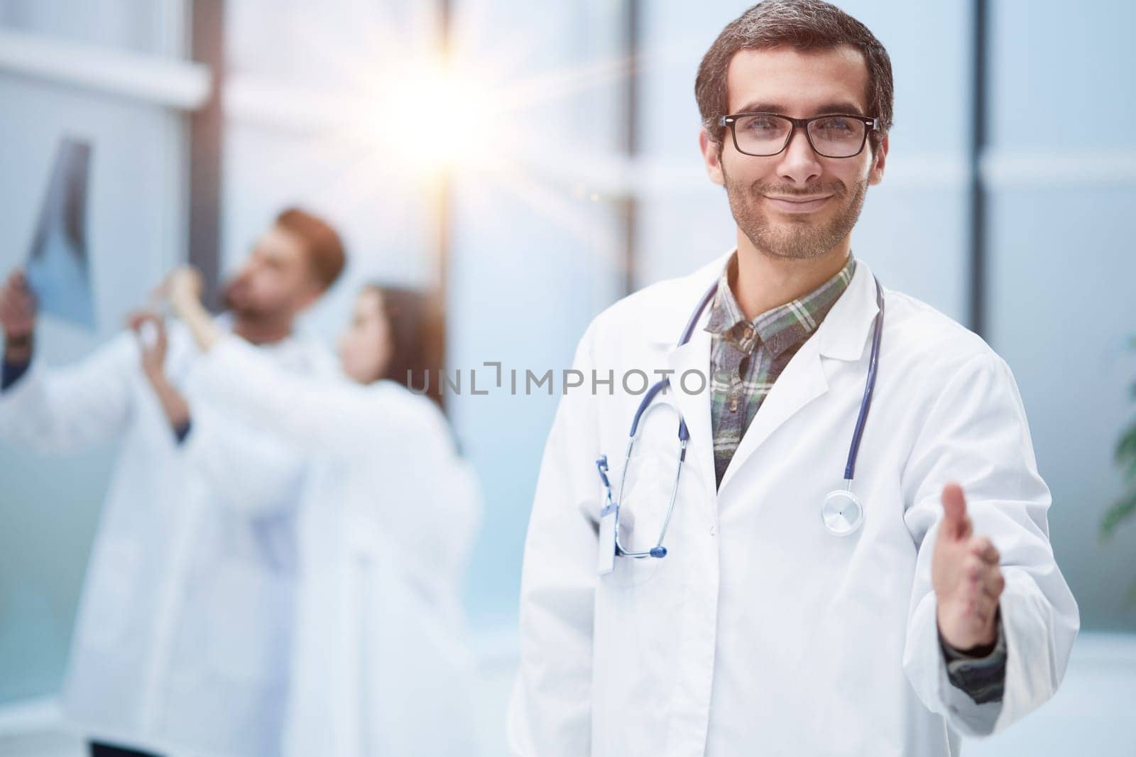image of a doctor extending his hand in greeting against the background of his colleagues