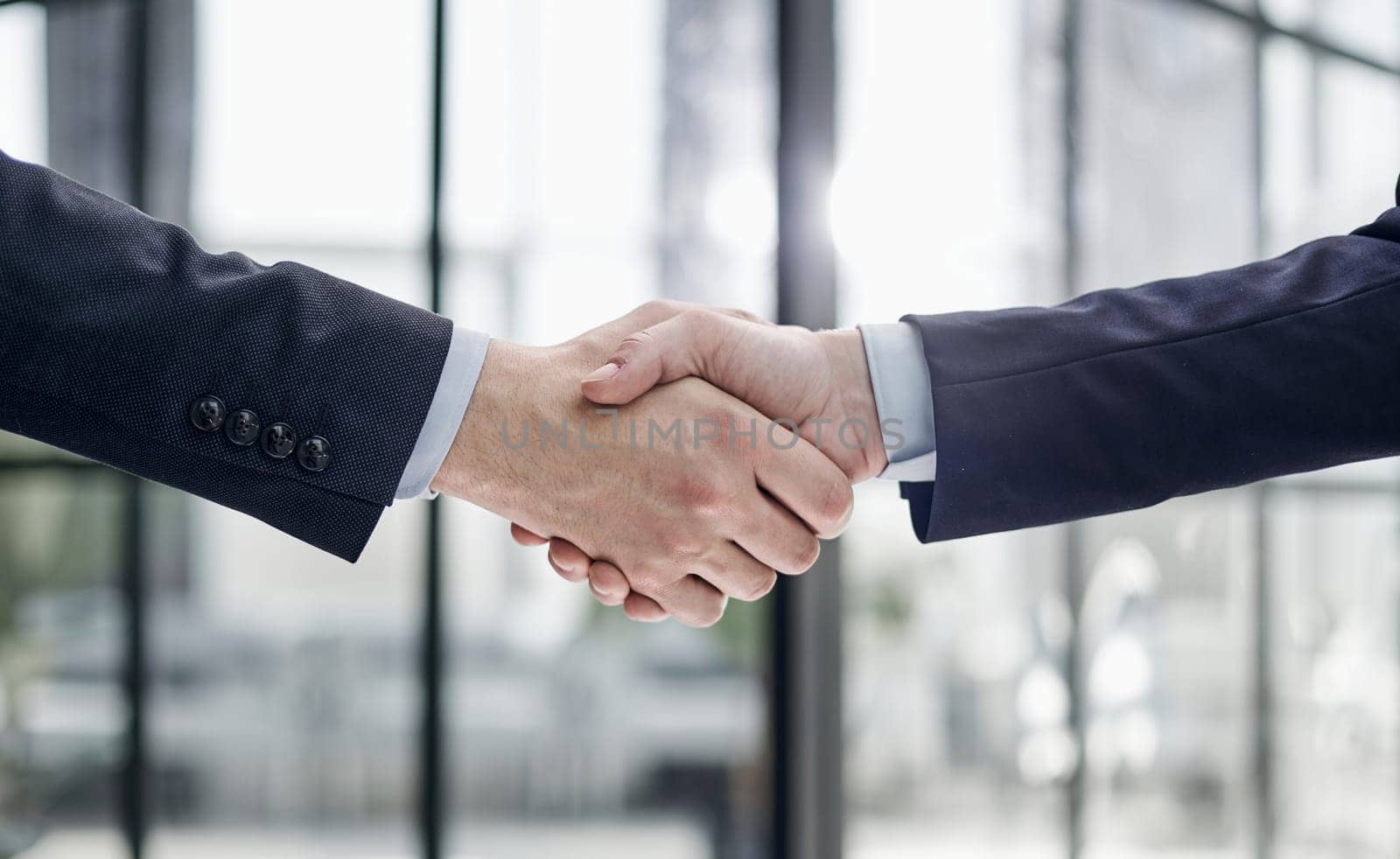 executives shaking hands in front of their manager and a colleague by Prosto