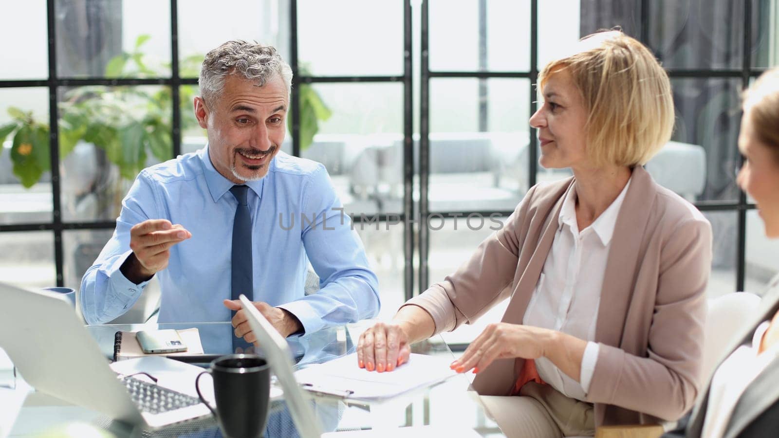 Casual business people around conference table in office by Prosto