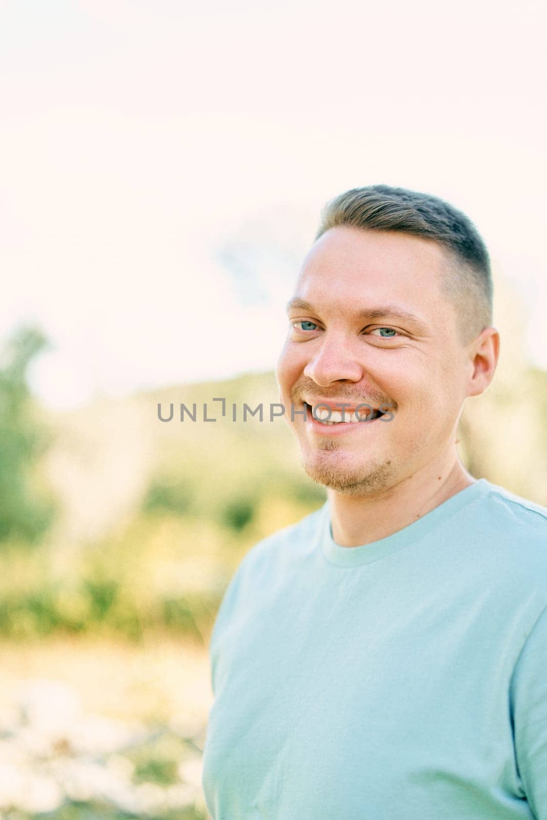 Laughing man stands in a sunny park. Portrait. High quality photo