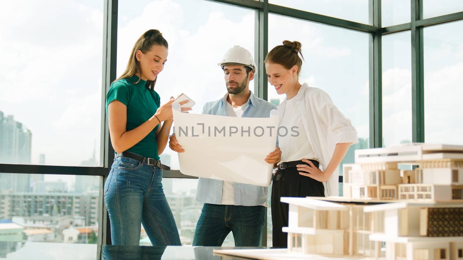 Professional architect engineer team talking, sharing, brainstorming about design while manager hold at project plan. Young architect holding plan while manager listen and point at plan. Tracery