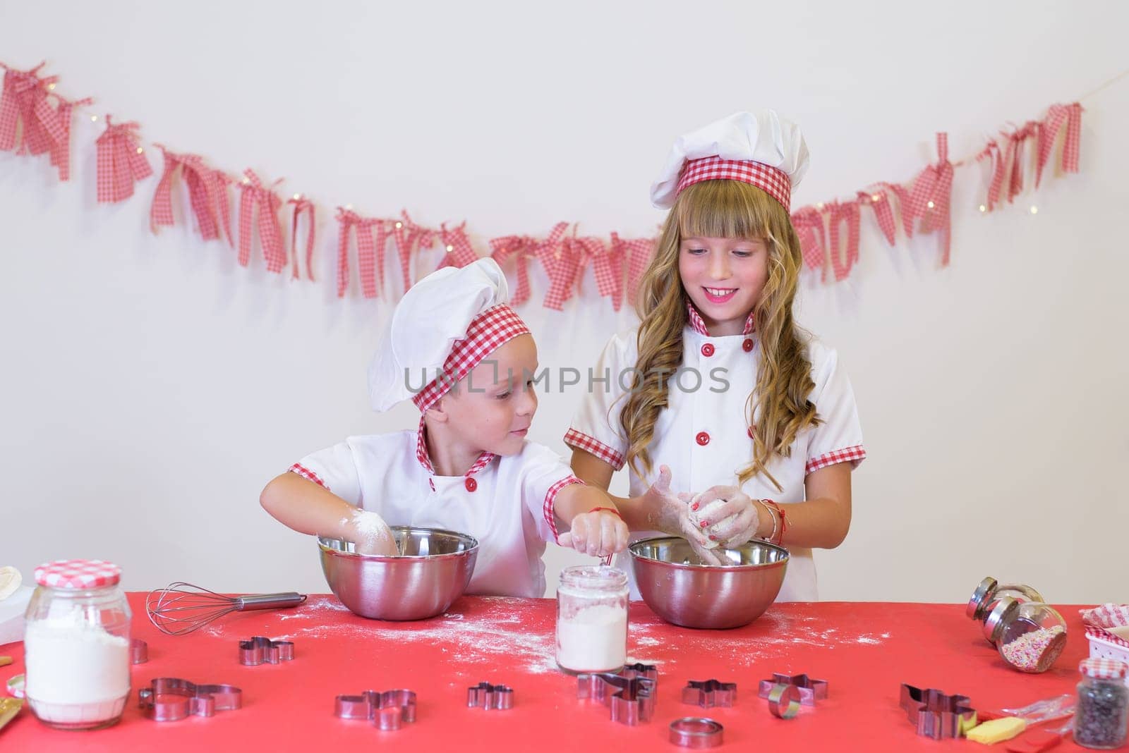 happy smiling children in apron and chef hat cooking cookies with flour, eggs, chocolate and water. Kitchen and family. Happy kids.