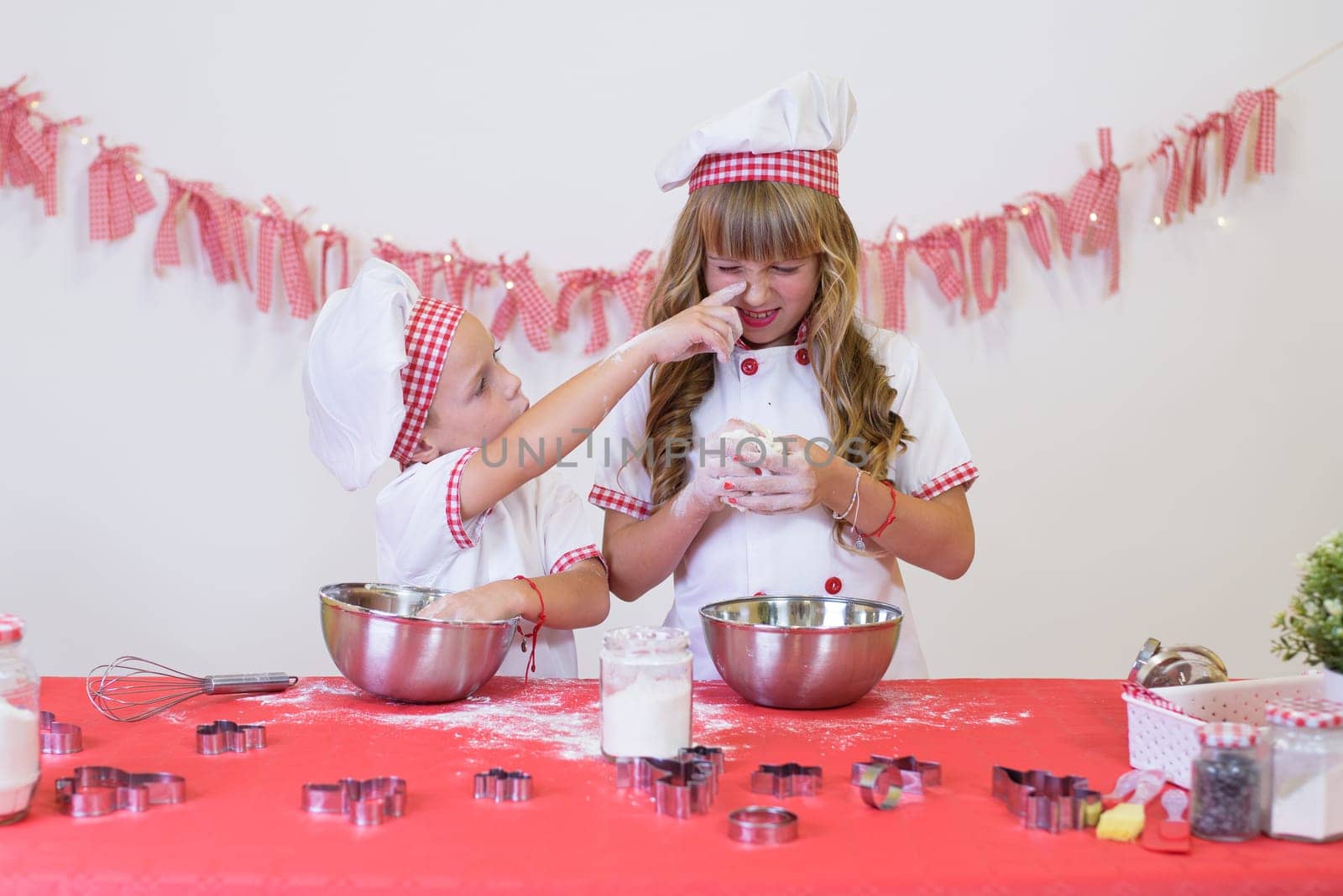 happy smiling children in apron and chef hat cooking cookies with flour, eggs, chocolate and water. Kitchen and family. Happy kids by jcdiazhidalgo