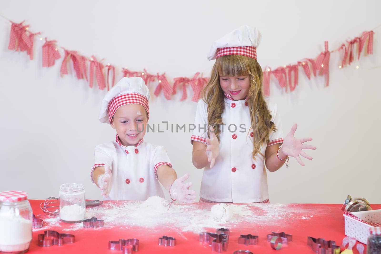 happy smiling children in apron and chef hat cooking cookies with flour, eggs, chocolate and water. Kitchen and family. Happy kids by jcdiazhidalgo
