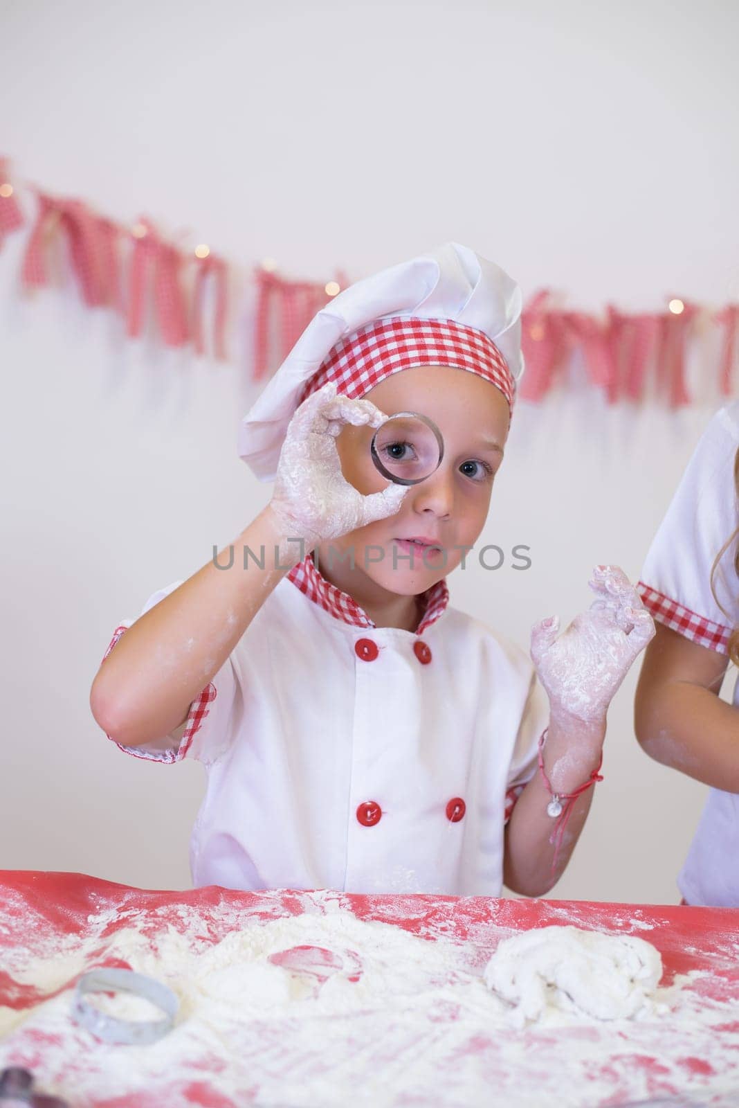 happy smiling child in apron and chef hat cooking cookies with flour, eggs, chocolate and water. Kitchen and family. Happy kids.