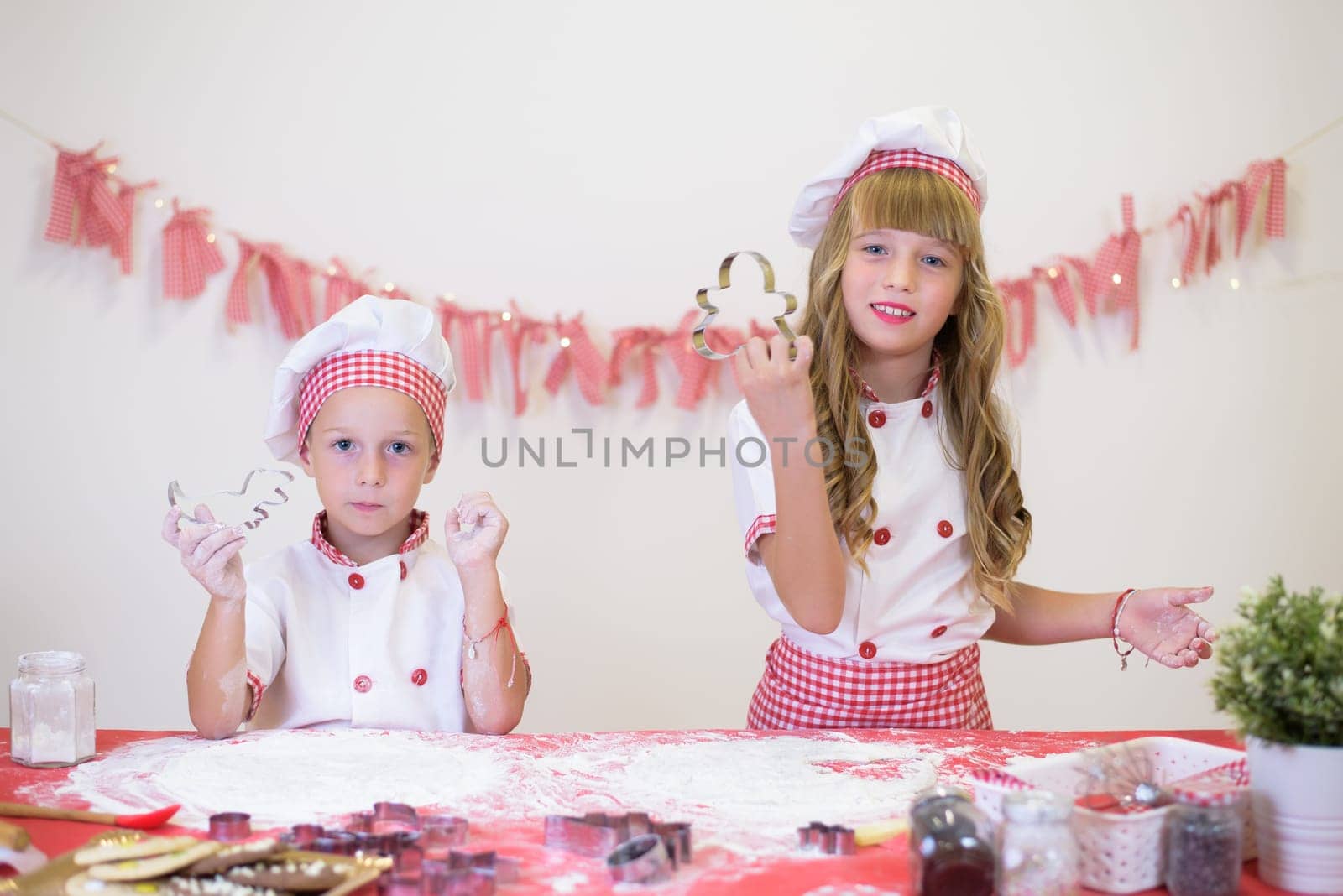 happy smiling children in apron and chef hat cooking cookies with flour, eggs, chocolate and water. Kitchen and family. Happy kids.